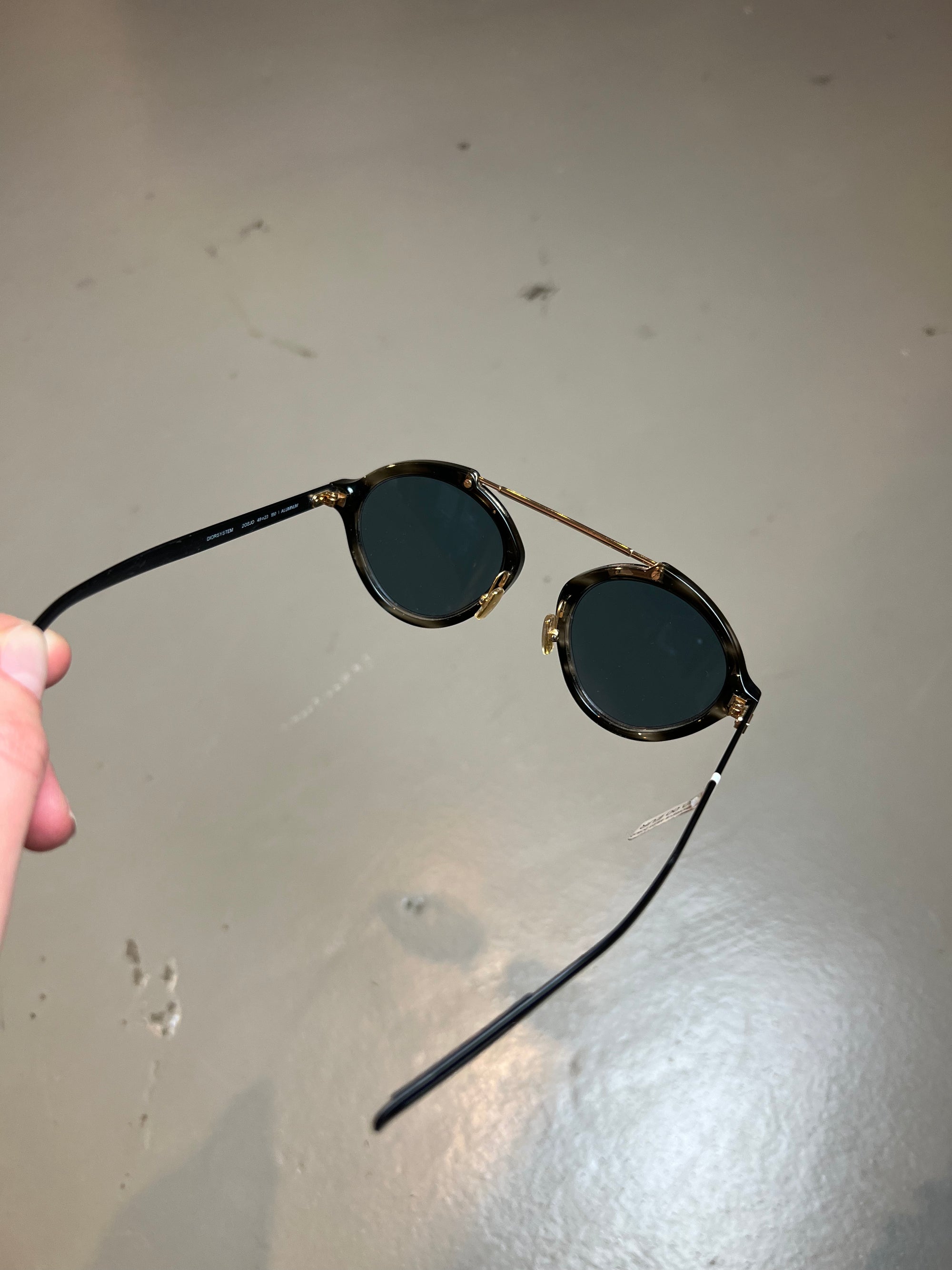 Detail-Produktbild einer Christian Dior Sonnenbrille vor grauem Hintergrund.