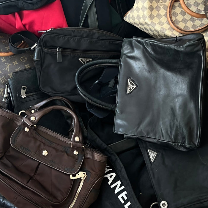 Zu sehen ist ein Haufen an Vintage Designer Handtaschen. Dabei sind Taschen von Prada, Louis Vuitton und Celine.