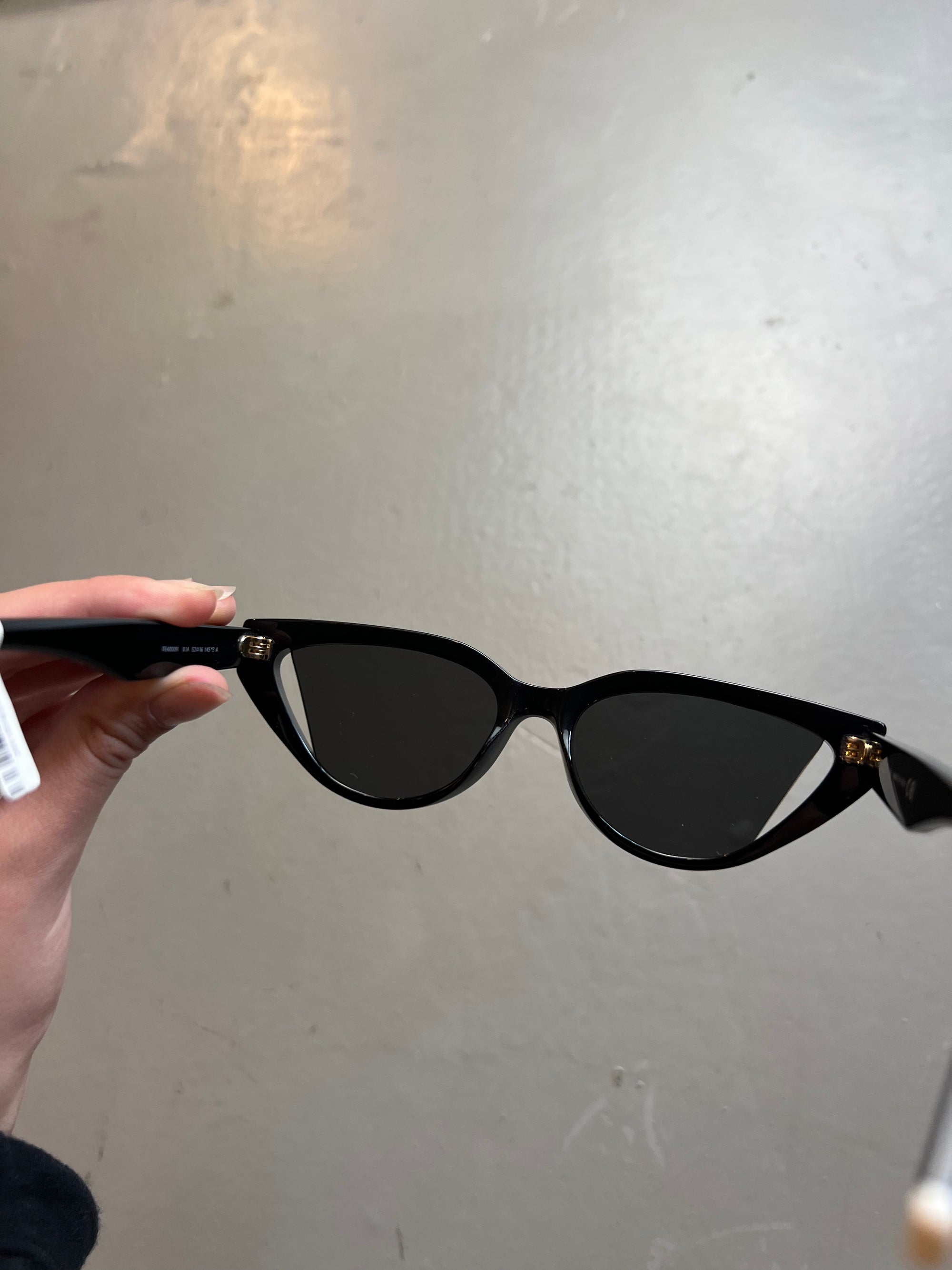 Detail-Produktbild von schwarzer Fendi Cat-Eye Sonnenbrille vor grauem Hintergrund.