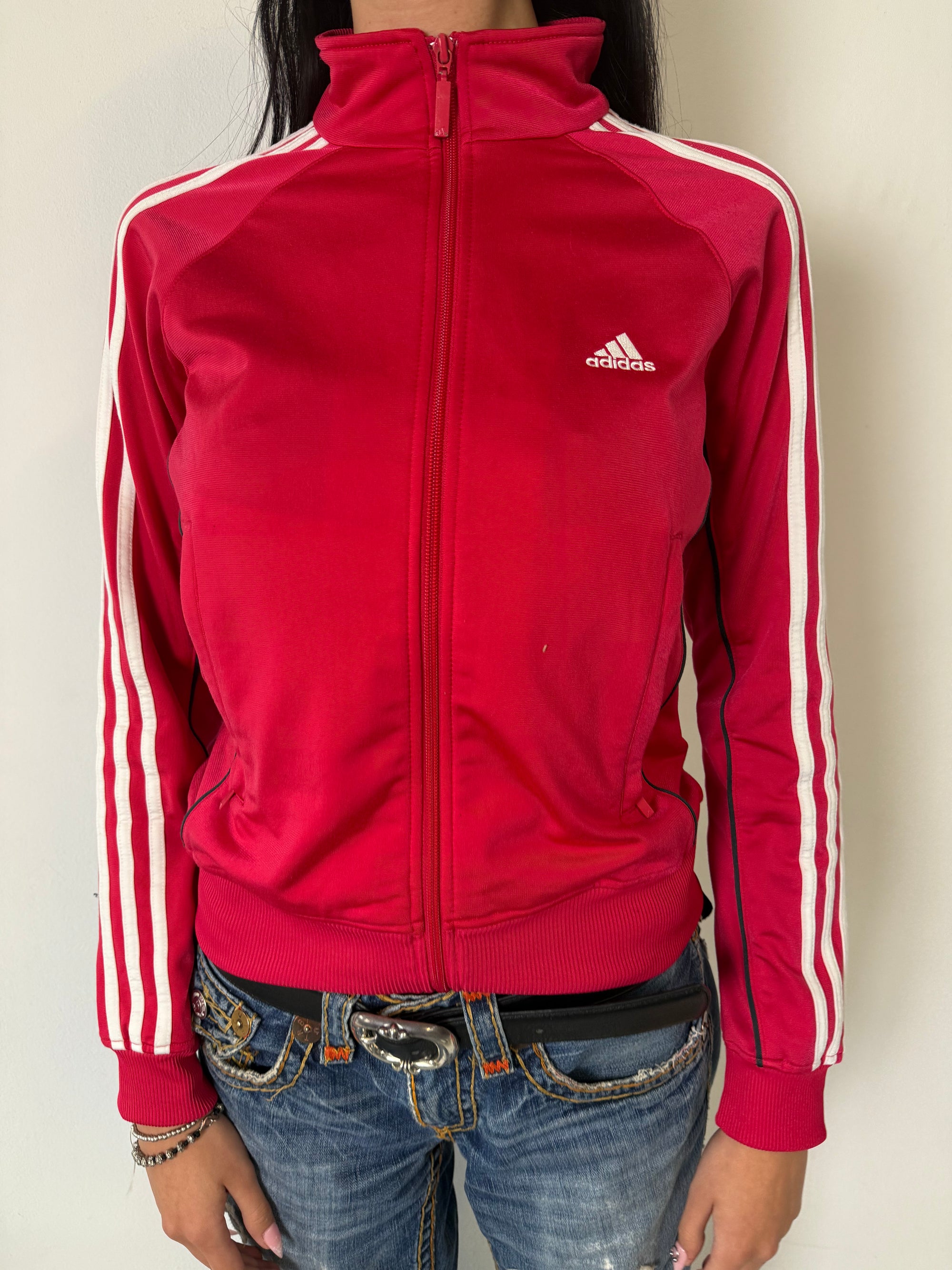 Eine Pinke Trackjacke von Adidas mit weißen Streifen auf den Ärmeln