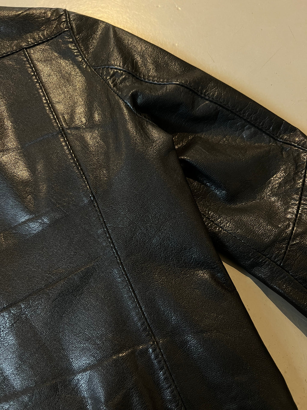 Nahaufnahme vom Leder der schwarzen Lederjacke auf grauem Boden 