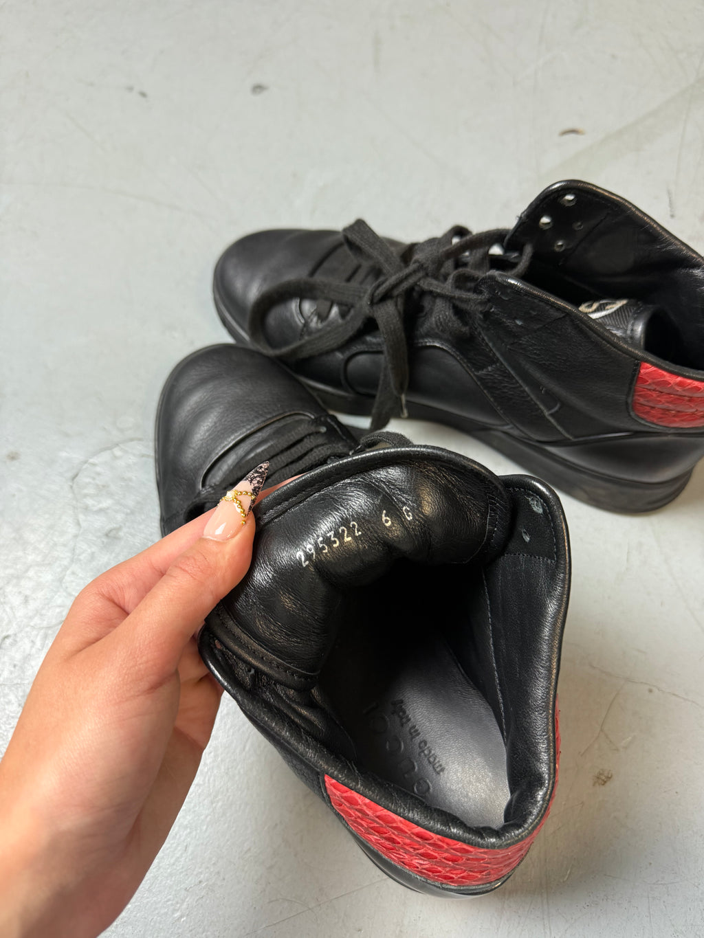 Schwarze gucci sneaker mit roten details hinten und roter sohle 