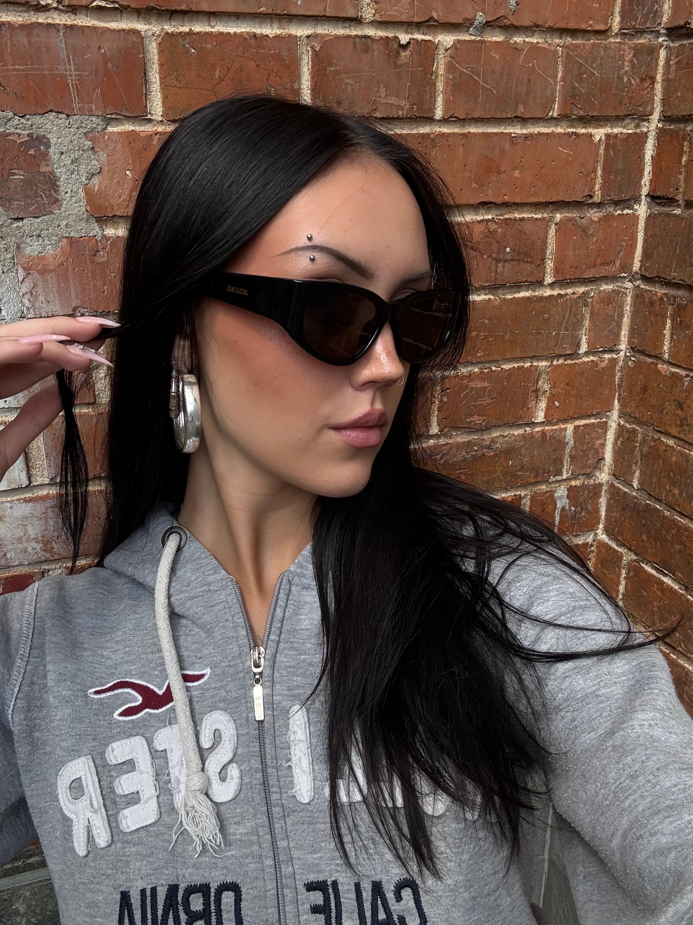 Eine schwarze Sonnenbrille von Jacquemus mit goldenem Schriftzug auf der Seite