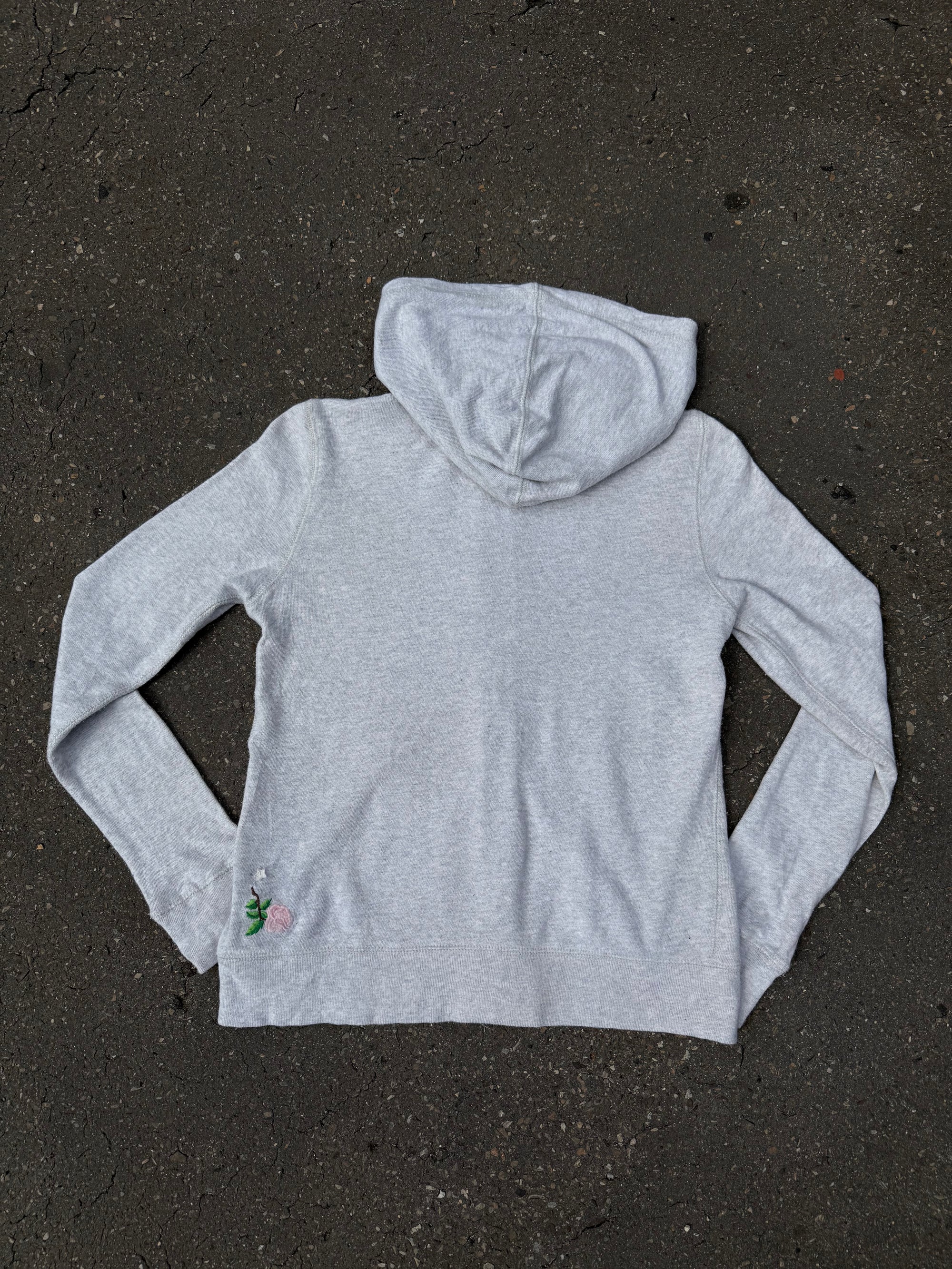 Ein grauer Zip Up Hoodie von Polo Ralph Lauren mit rosa Polo Aufdruck auf der Brust und kleinen patches überall verteilt in XS