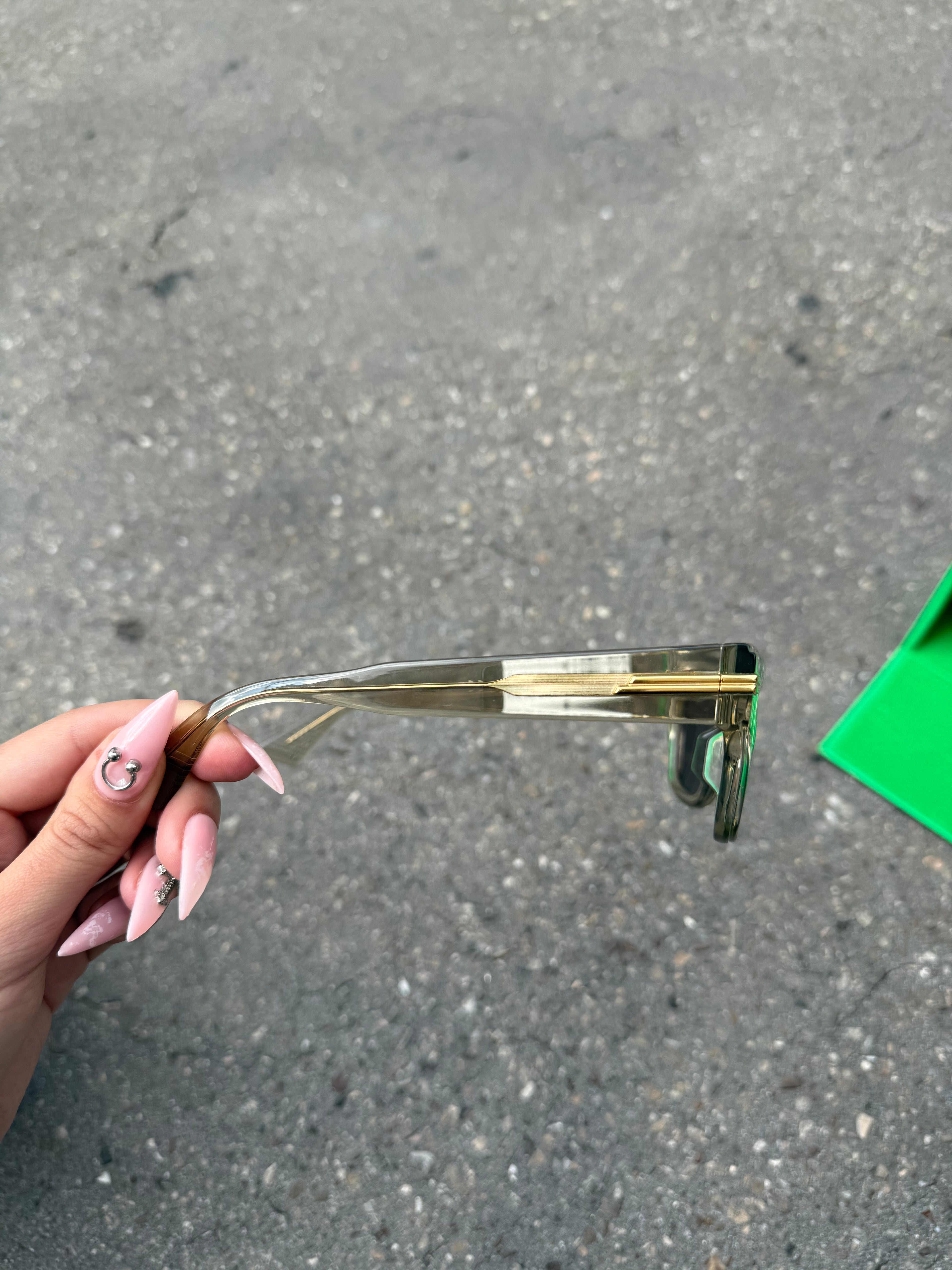 Eine beige transparente Sonnenbrille von Bottega Veneta mit Gold Details