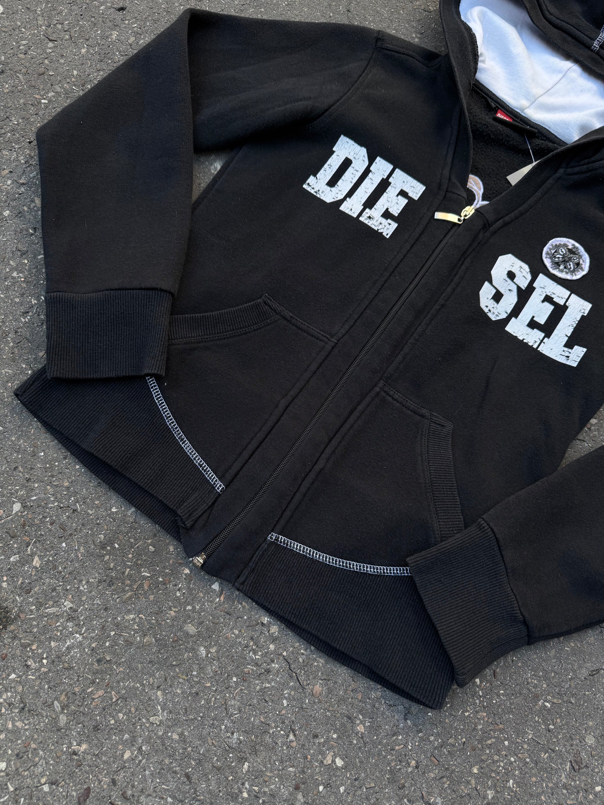 Ein schwarzer Zip Up Hoodie von Diesel mit dem Logo in weiß auf der Vorderseite und einem weißen Print auf der Rückseite