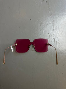 Detail-Produktbild von einer pinken Christian Dior Sonnenbrille ohne Rahmen vor grauem Hintergrund.