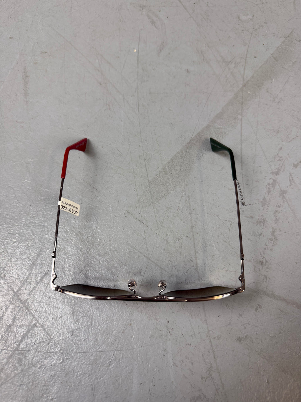 Eine eckige Sonnenbrille von gucci mit dunklen Gläsern und roten und grünen Elementen an den Bügeln 