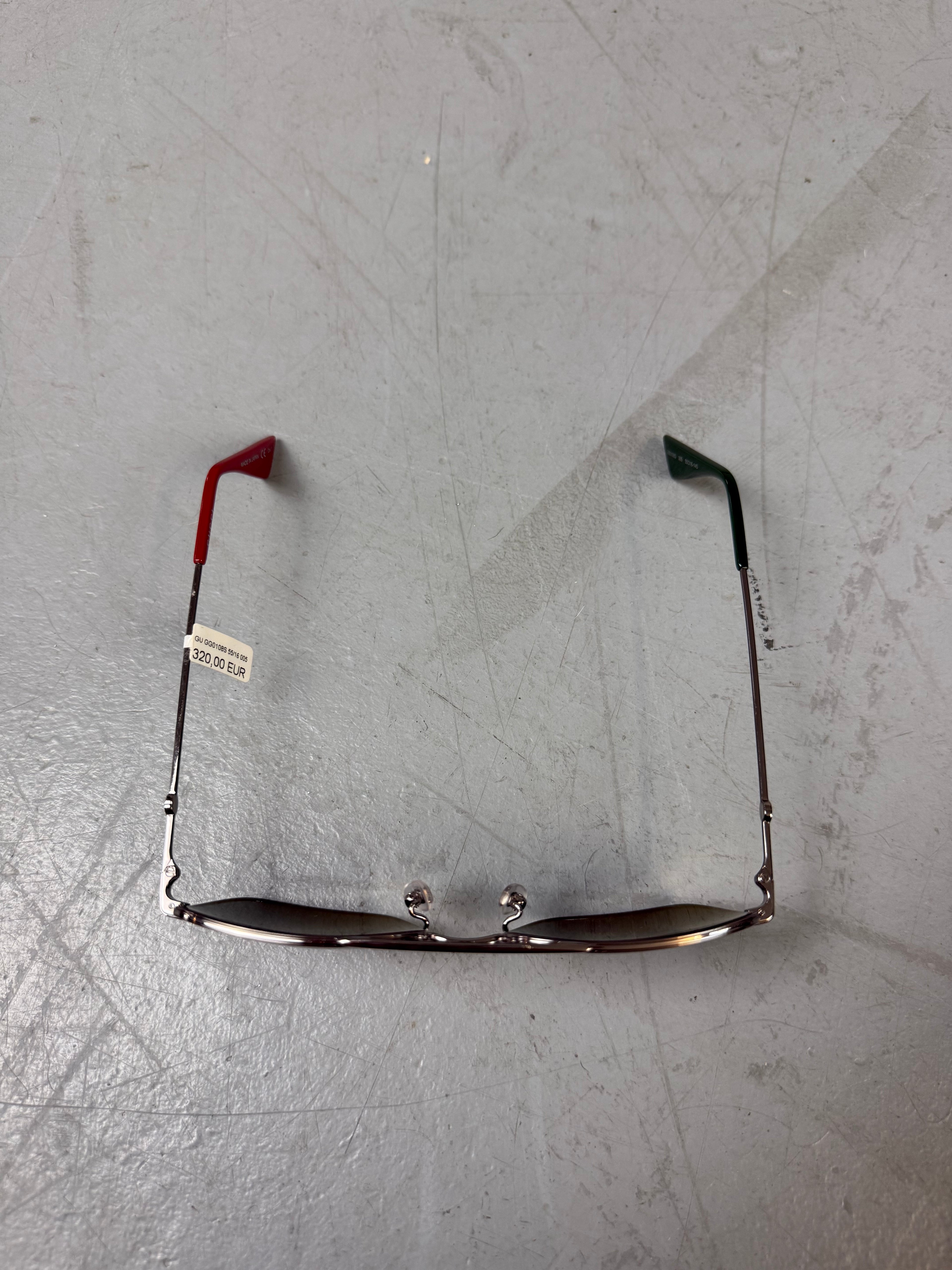 Eine eckige Sonnenbrille von gucci mit dunklen Gläsern und roten und grünen Elementen an den Bügeln 