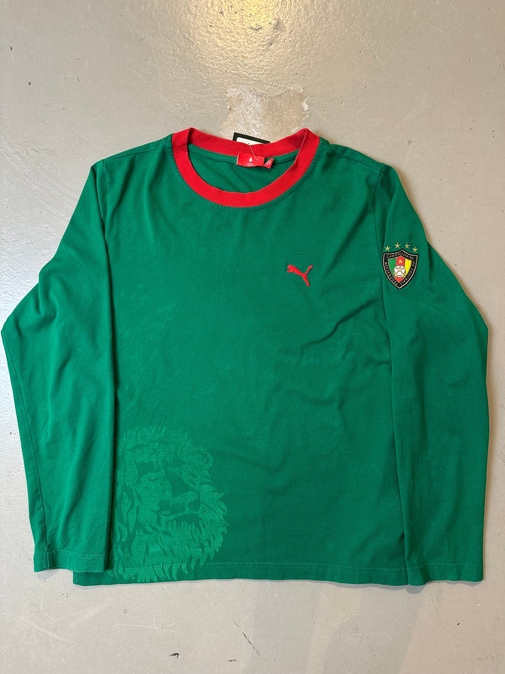 Ein grünes Longsleeve von Pomo mit roten Details an Ärmel und Kragen und der Aufschrift Cameroon auf dem Rücken in L
