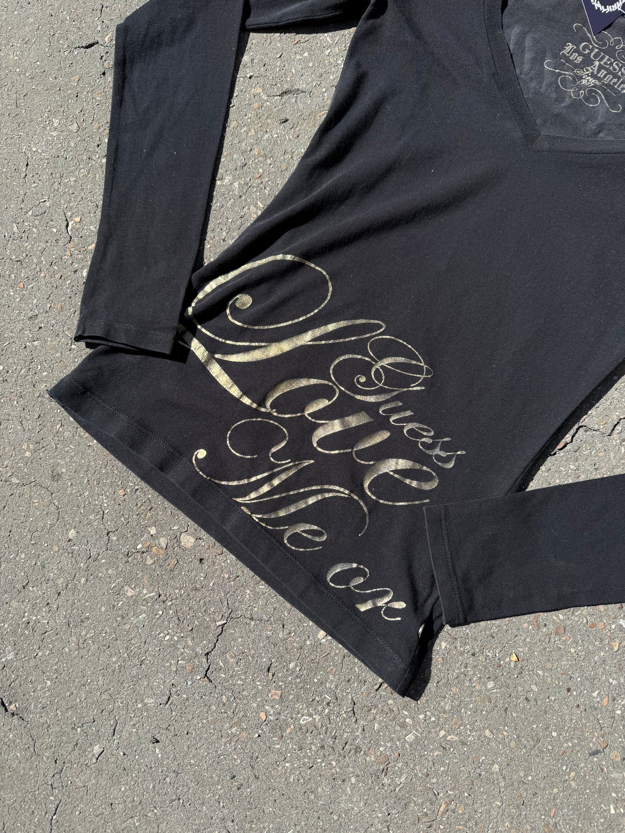 Ein schwarzes Longsleeve von Guess mit goldenem Schriftzug auf der Vorderseite und Rückseite Slim Fit