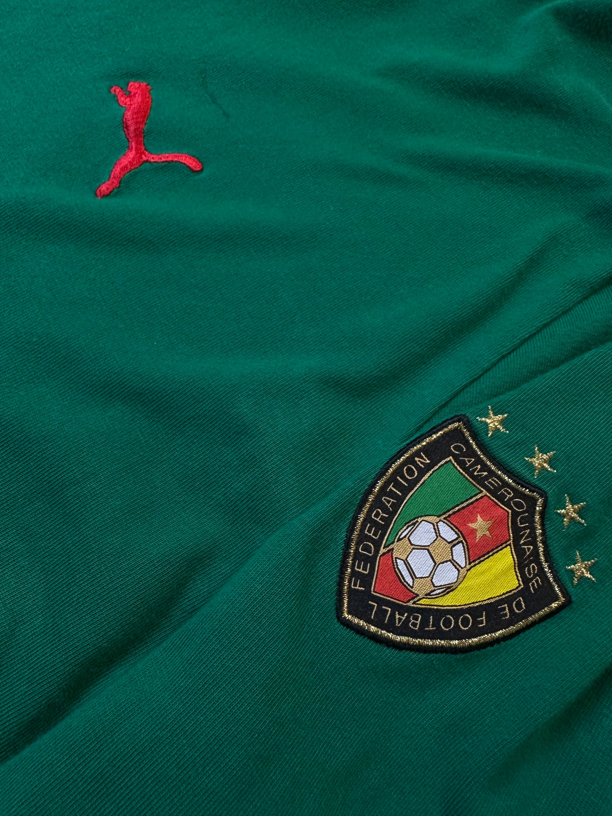 Ein grünes Longsleeve von Pomo mit roten Details an Ärmel und Kragen und der Aufschrift Cameroon auf dem Rücken in L