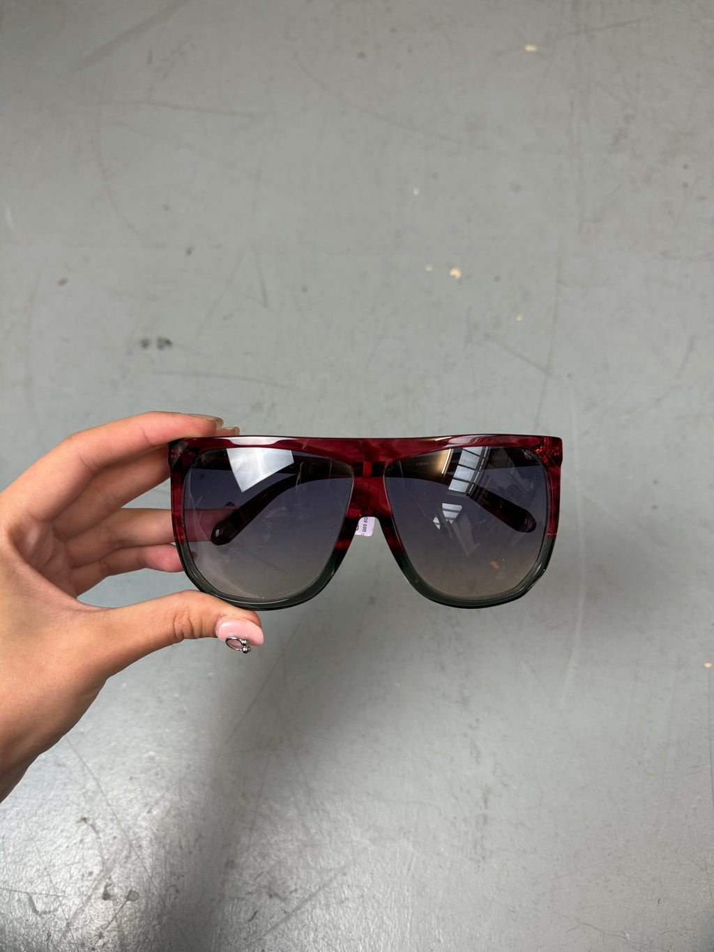 Eine Loewe Sonnenbrille mit großen dunklen Gläsern und rotem Gestell 