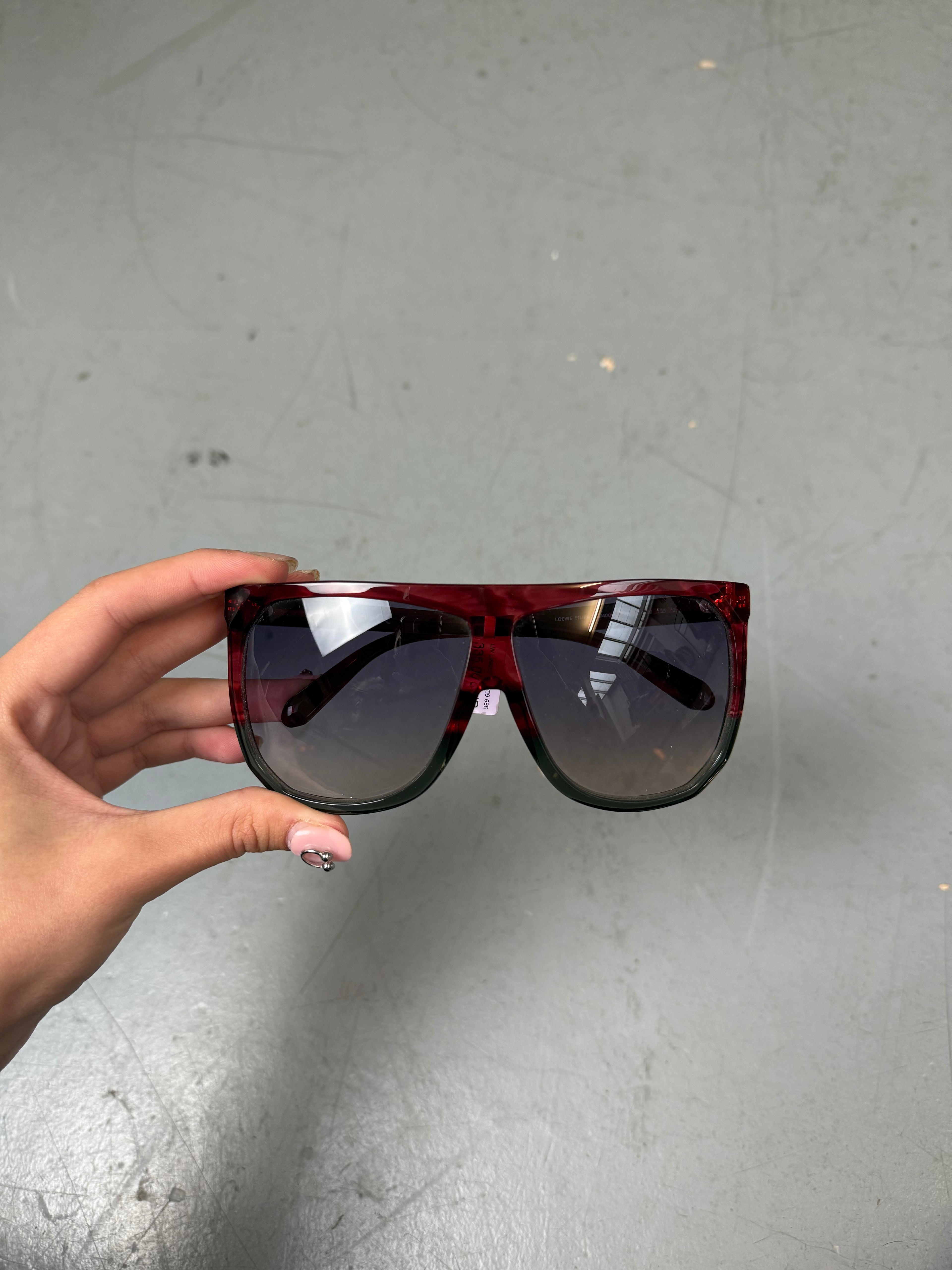 Eine Loewe Sonnenbrille mit großen dunklen Gläsern und rotem Gestell 