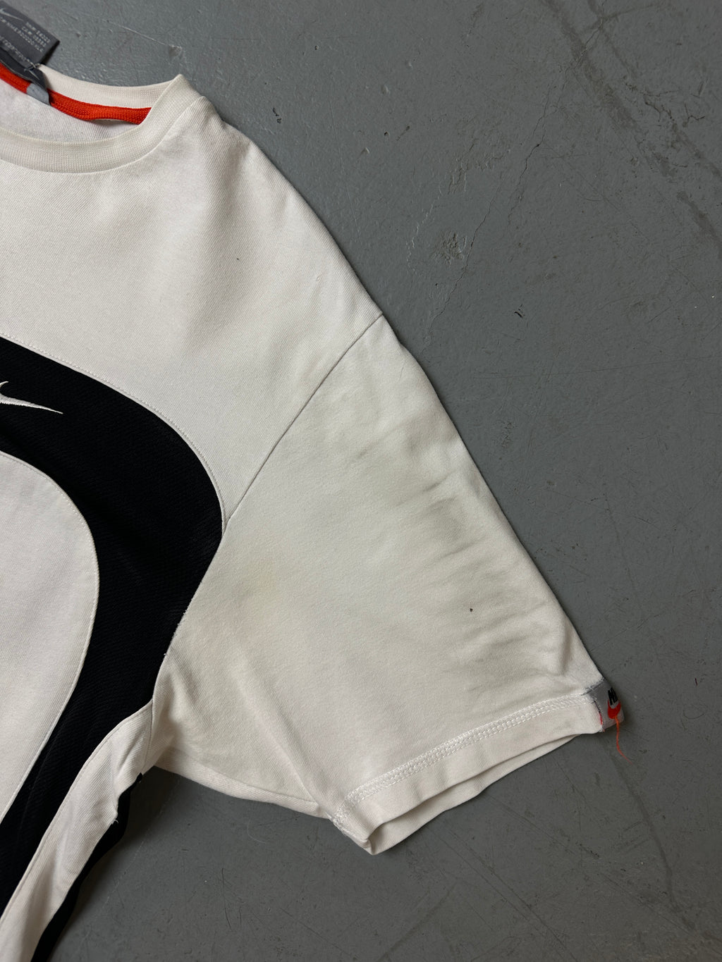 Detailliertes Produktbild von schwarz weißem Nike Tshirt auf grauem Boden 