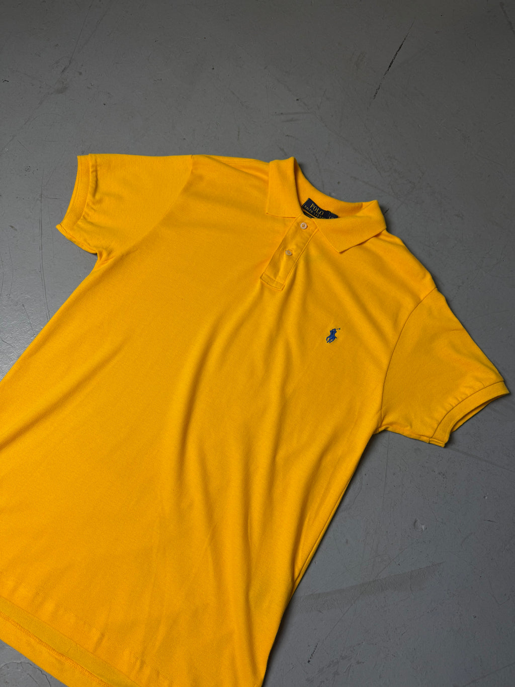 Ein gelbes Polo von Ralph Lauren mit blauem Reiter auf der Brust in L