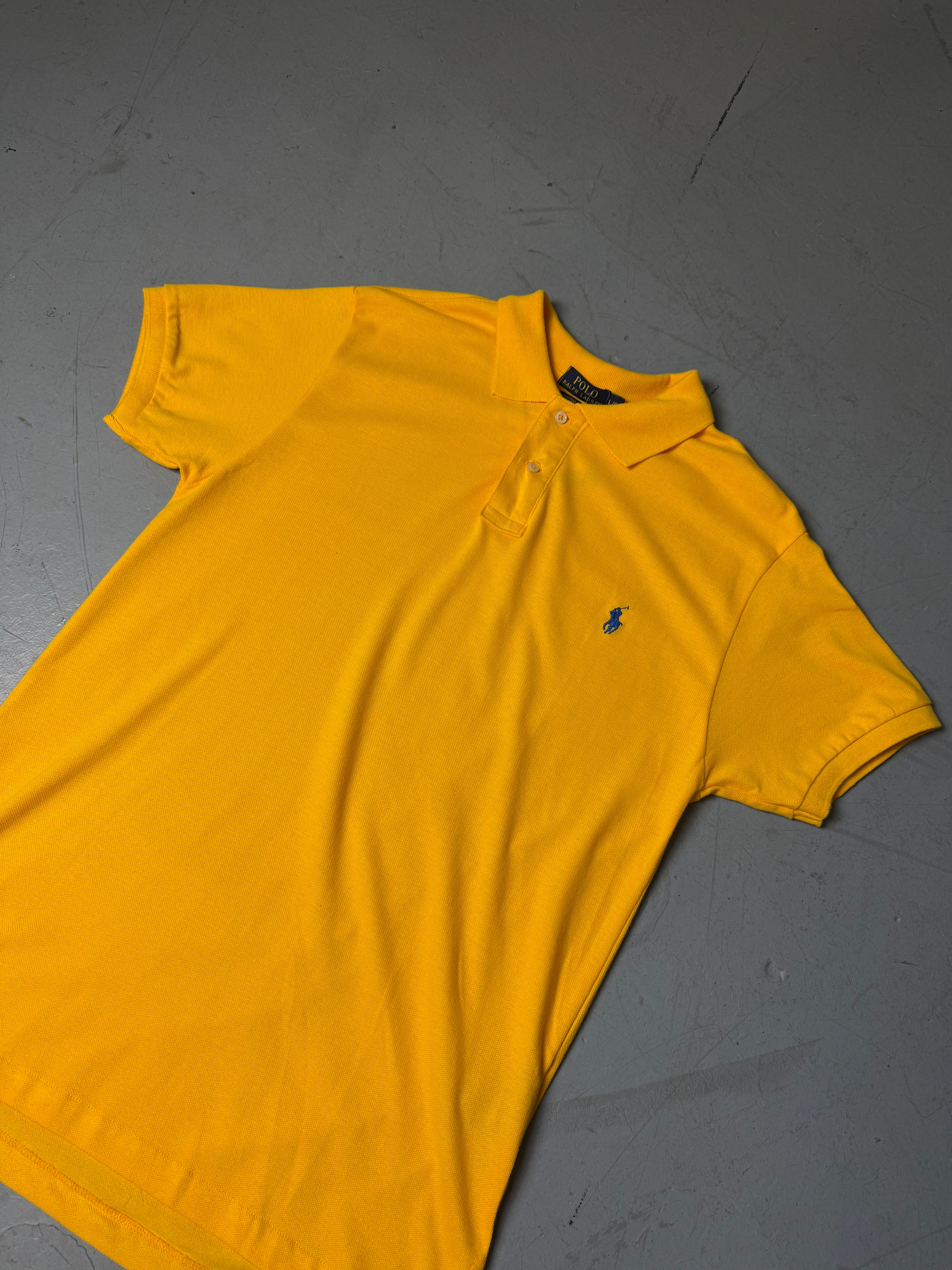 Ein gelbes Polo von Ralph Lauren mit blauem Reiter auf der Brust in L