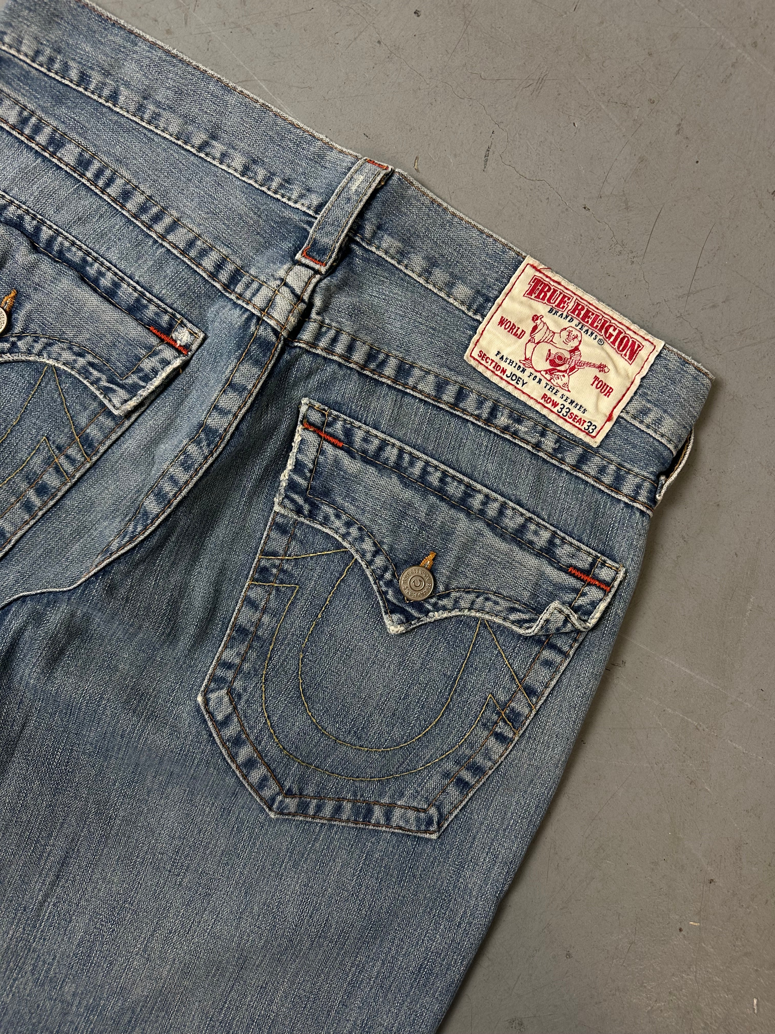 Eine blau-graue baggy True Religion Jeans mit weißen Hufeisen Stitching