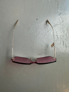 Detail-Produktbild von einer pinken Christian Dior Sonnenbrille ohne Rahmen vor grauem Hintergrund.