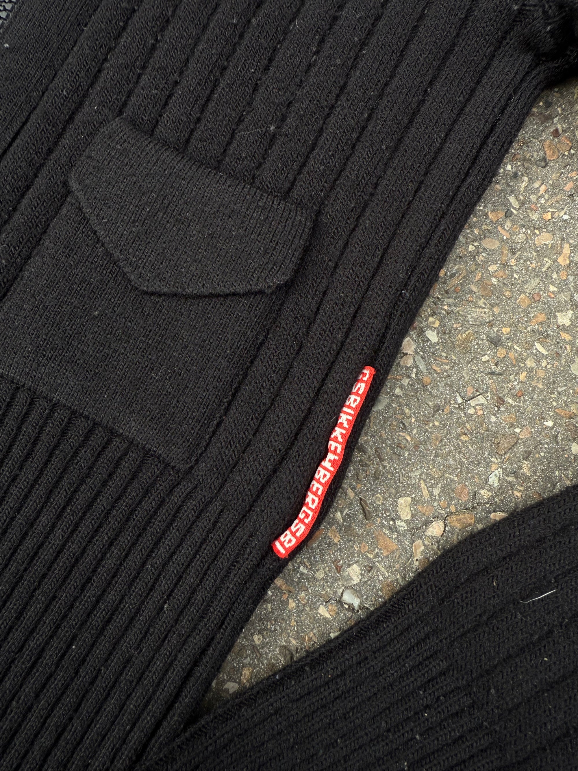 Ein schwarzer Strick Zipper von Dirk Bikkembergs mit roter Schlaufe am Reißverschluss in XS