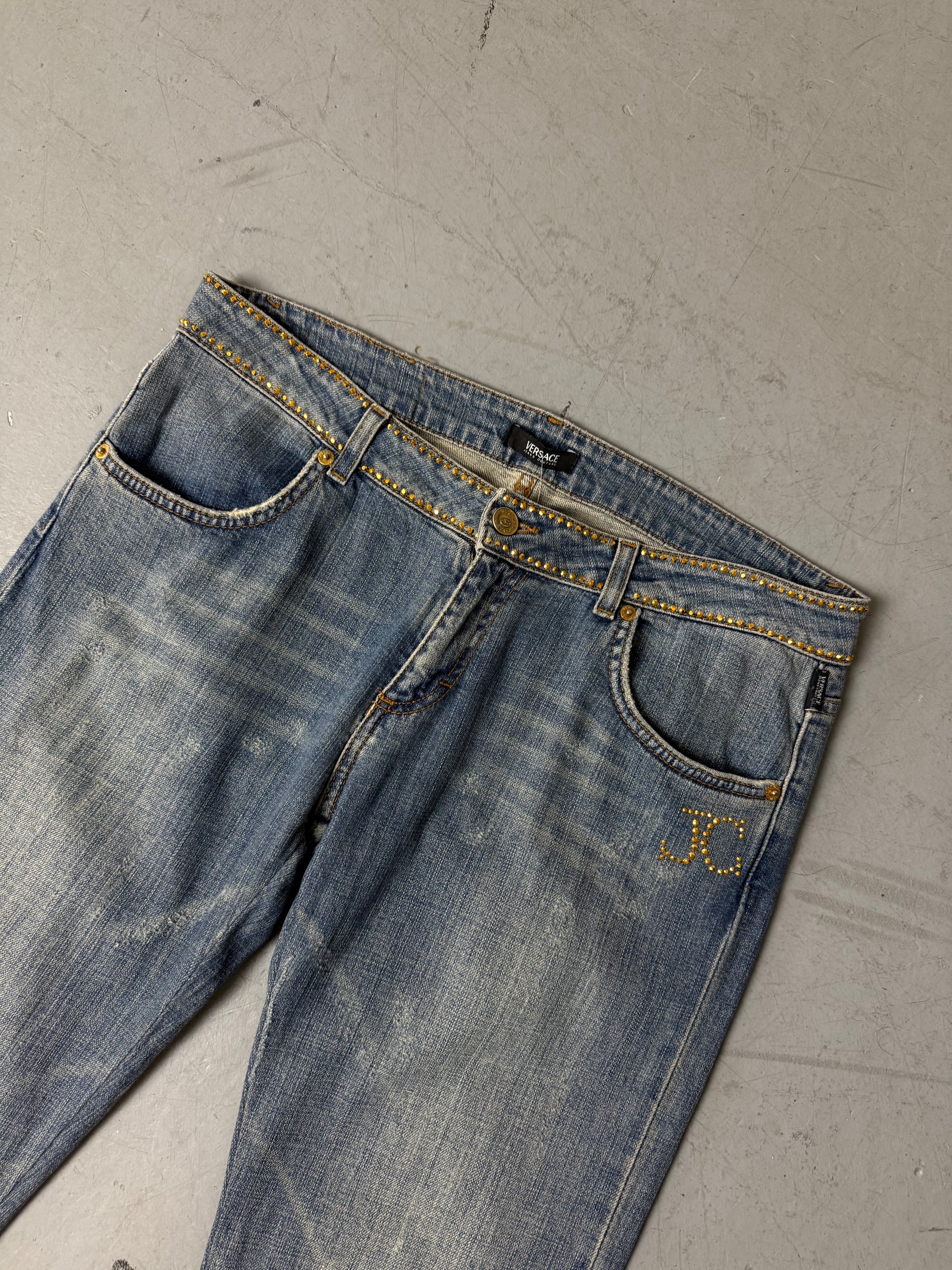 Eine low waist blue washed Versace Jeans im Bootcut Schnitt mit goldenen rhinestones um den Bund und am Bein 