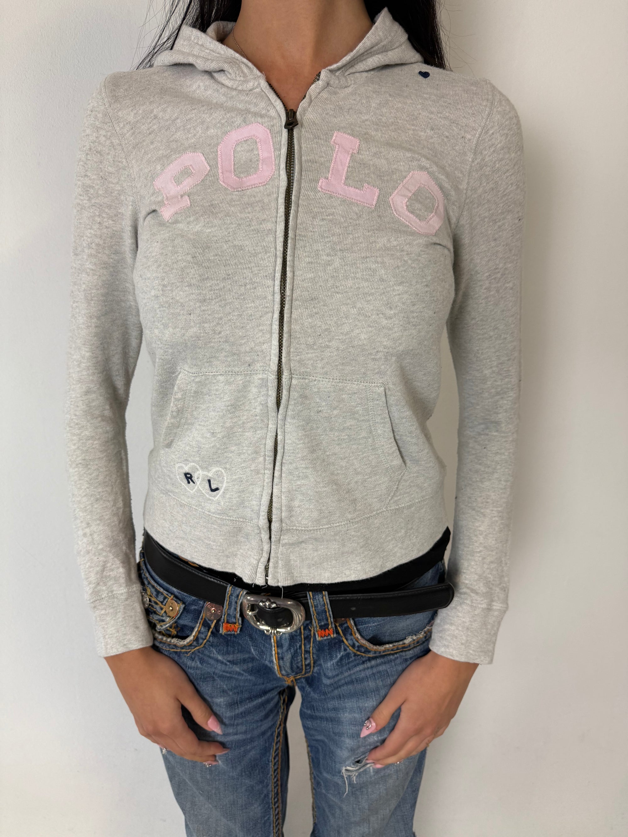 Ein grauer Zip Up Hoodie von Polo Ralph Lauren mit rosa Polo Aufdruck auf der Brust und kleinen patches überall verteilt in XS