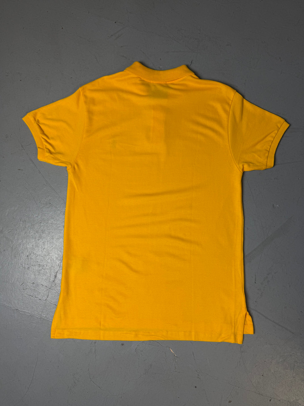 Ein gelbes Polo von Ralph Lauren mit blauem Reiter auf der Brust in L