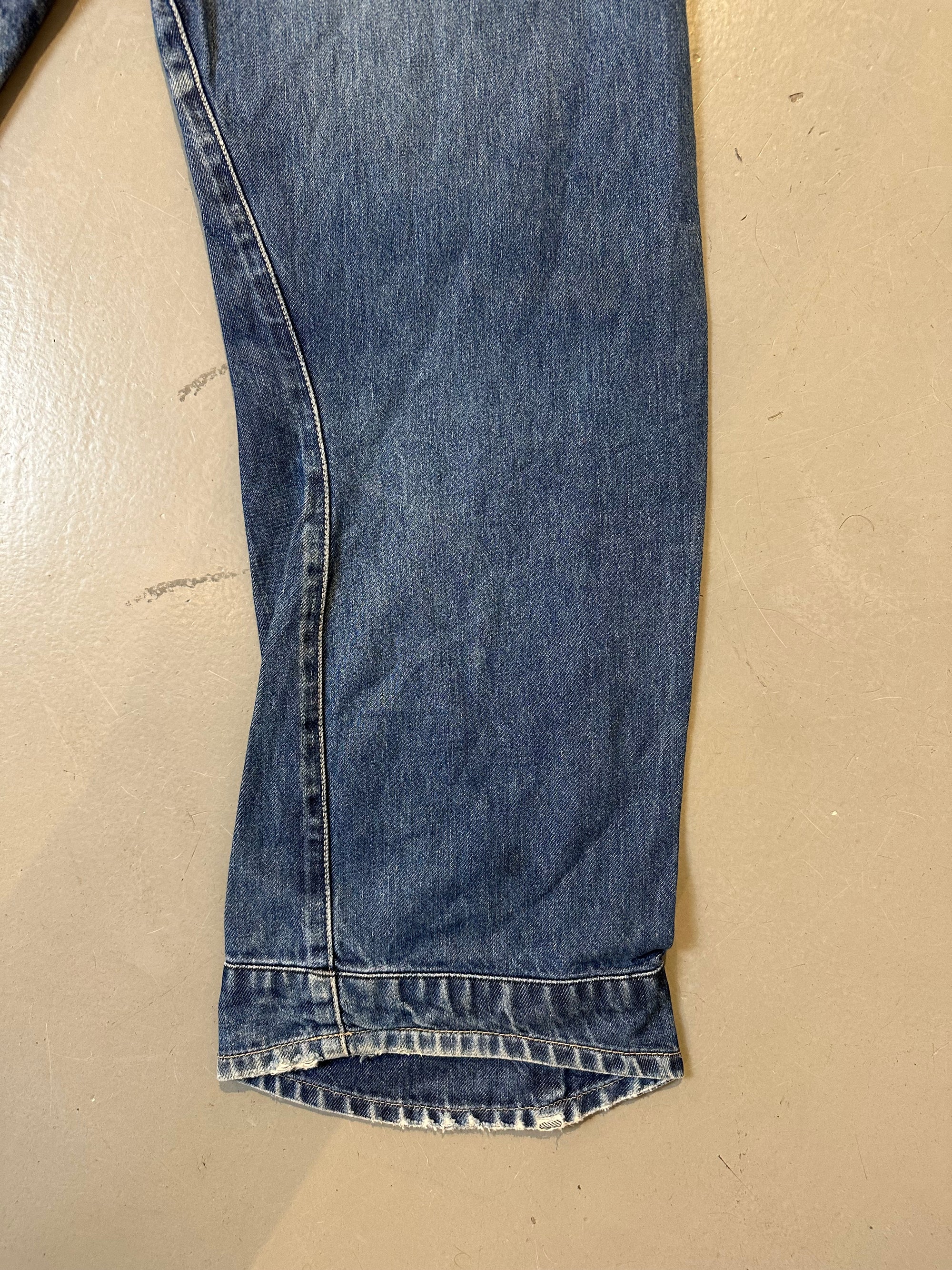 Detailliertes Produktbild von blauer Vintage Levis Hose Größe M/L auf grauem Boden