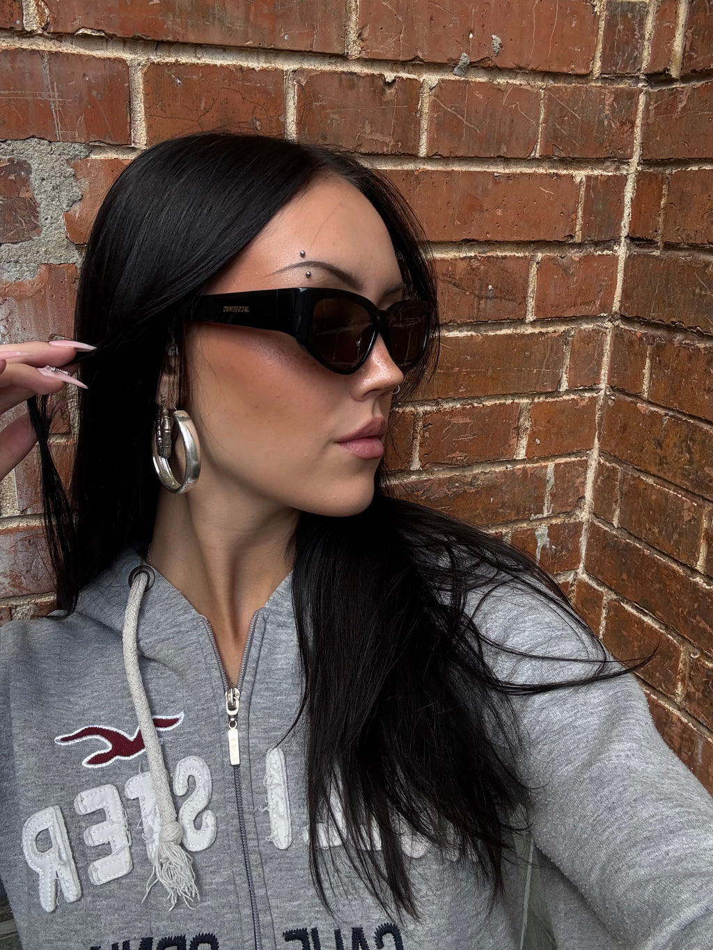 Eine schwarze Sonnenbrille von Jacquemus mit goldenem Schriftzug auf der Seite