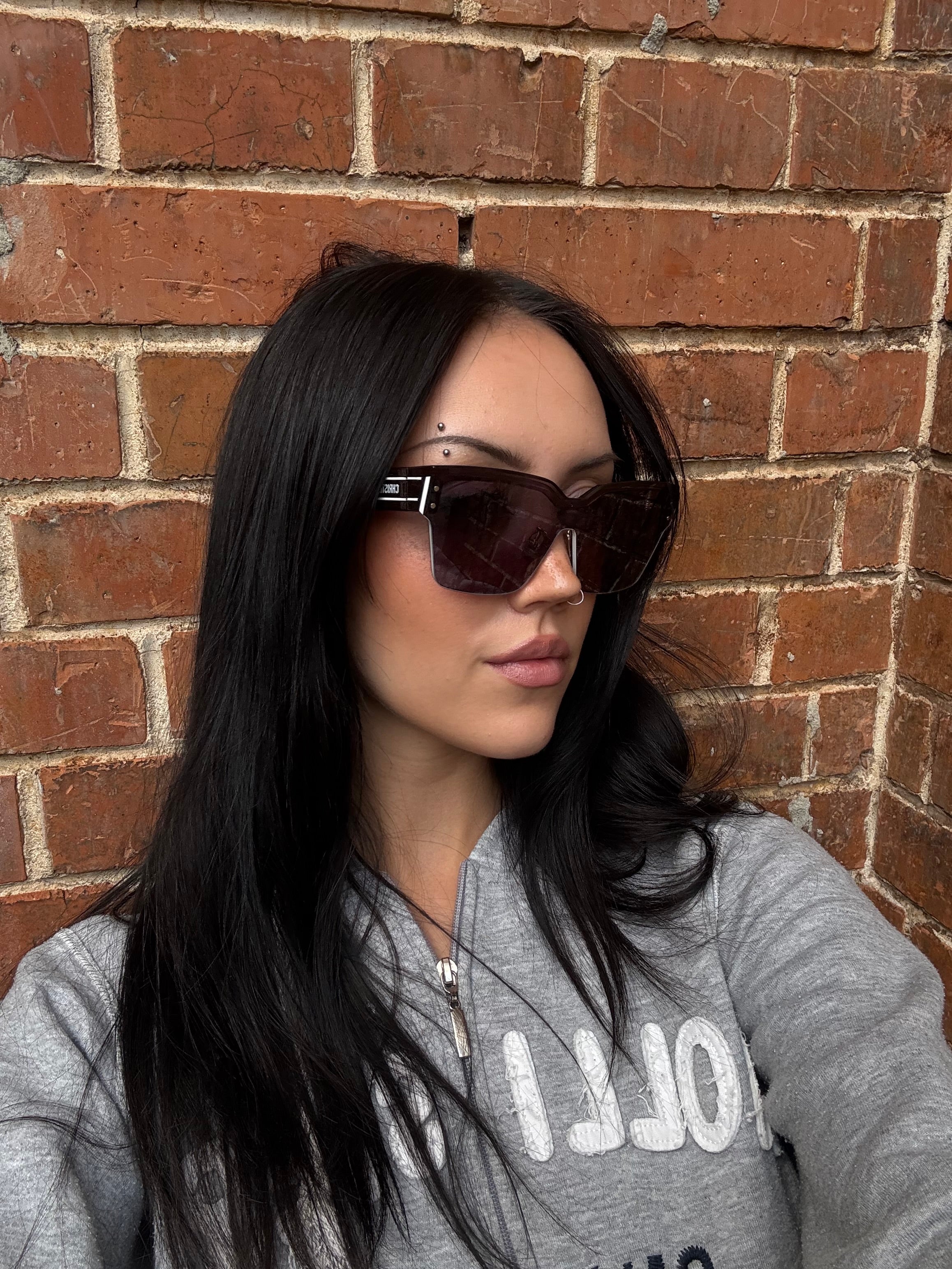 Eine schwarze Sonnenbrille von Dior mit dem Monogram auf den Gläsern und dem Markennamen auf den Bügeln