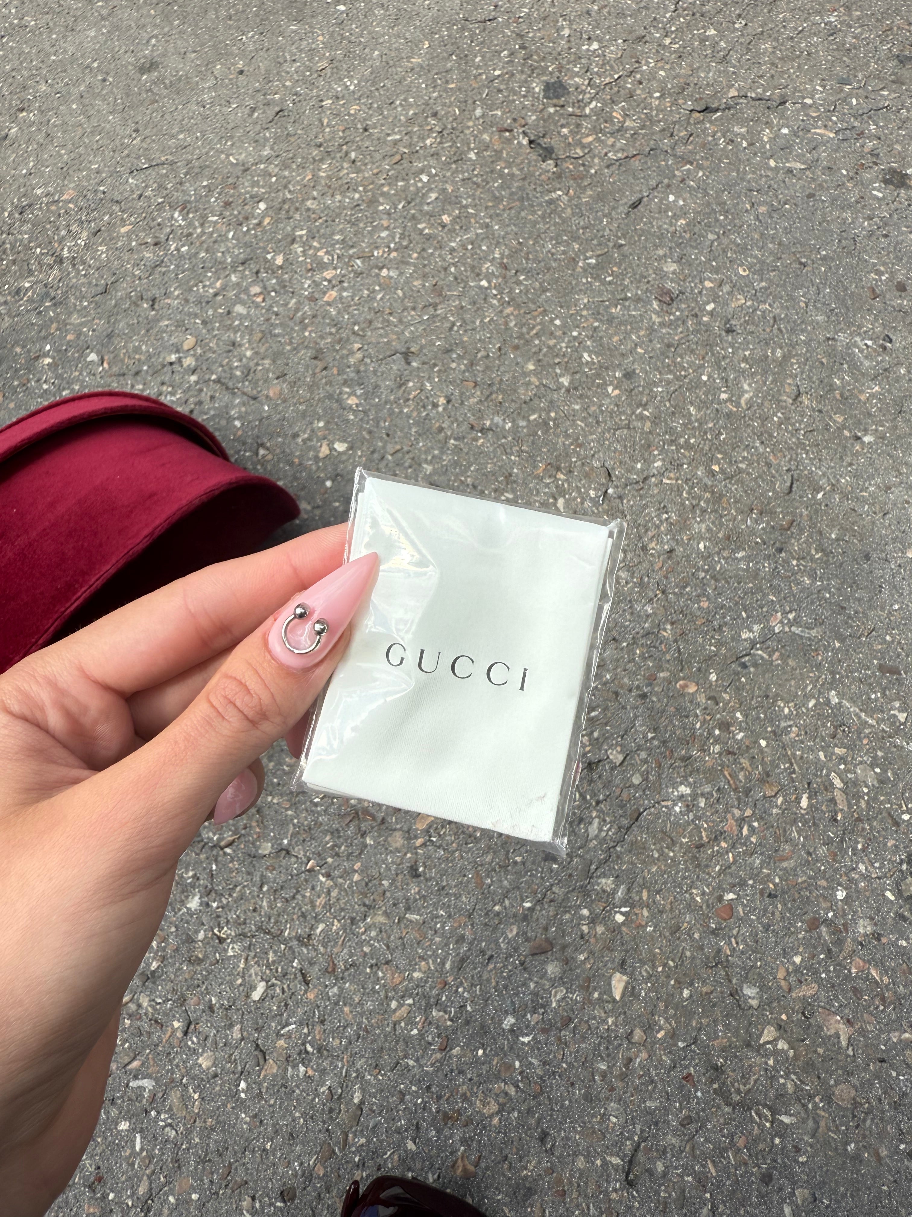 Eine burgunderrote Sonnenbrille von Gucci mit dem Logo in Gold an der Seite und großen quadratischen Gläsern