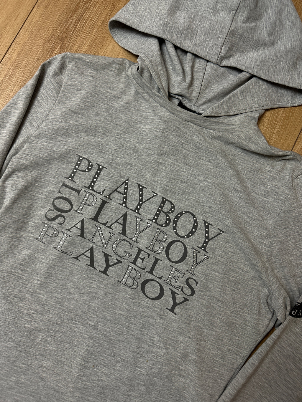 Ein grauer hoodie von Playboy mit Logo strasssteinchen auf der Brust und Patch auf dem Arm im y2k Stil 