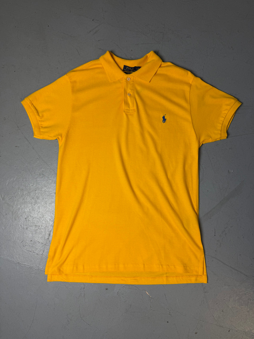 Ein gelbes Polo von Ralph Lauren mit blauem Reiter auf der Brust in L
