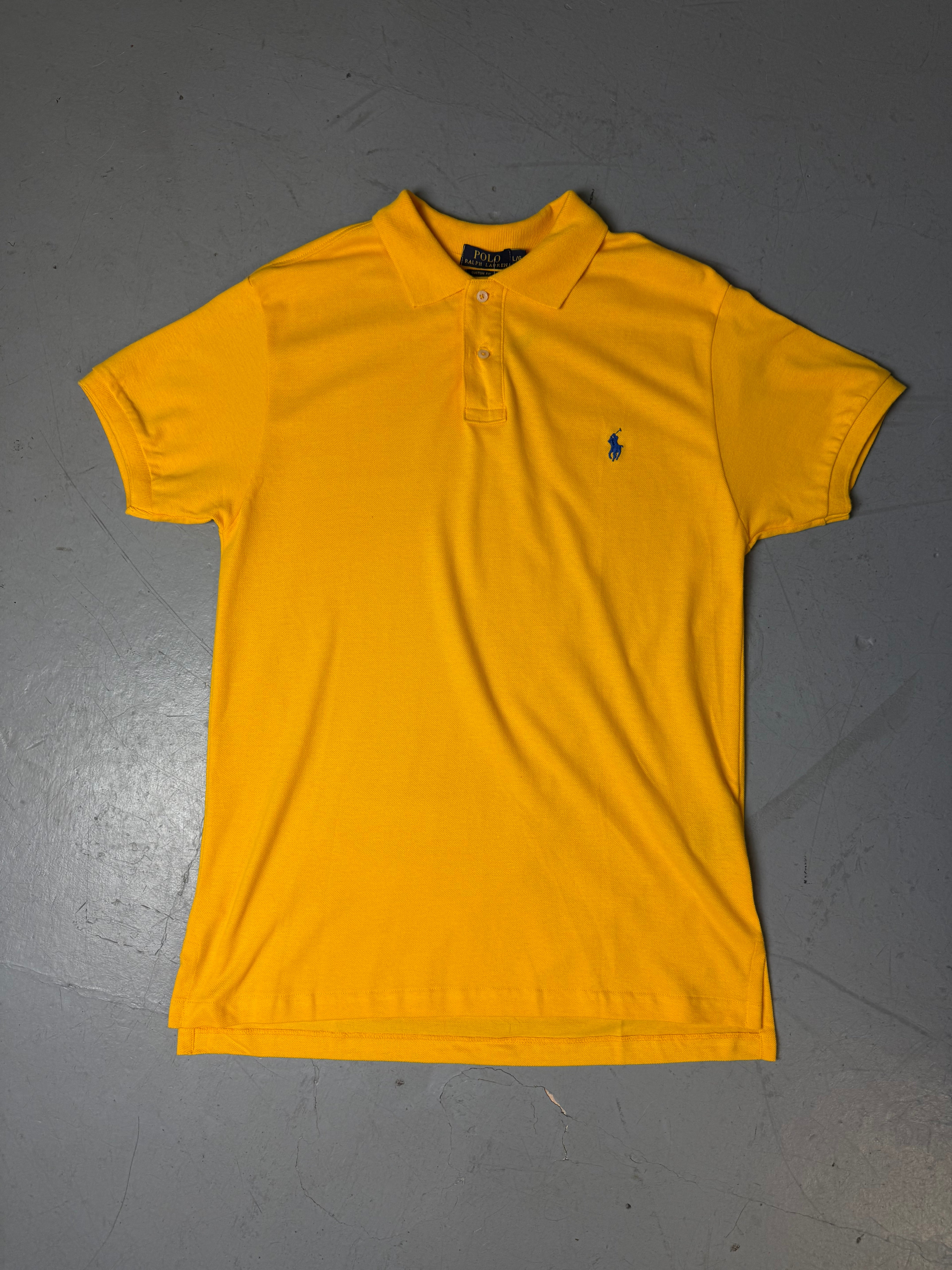 Ein gelbes Polo von Ralph Lauren mit blauem Reiter auf der Brust in L