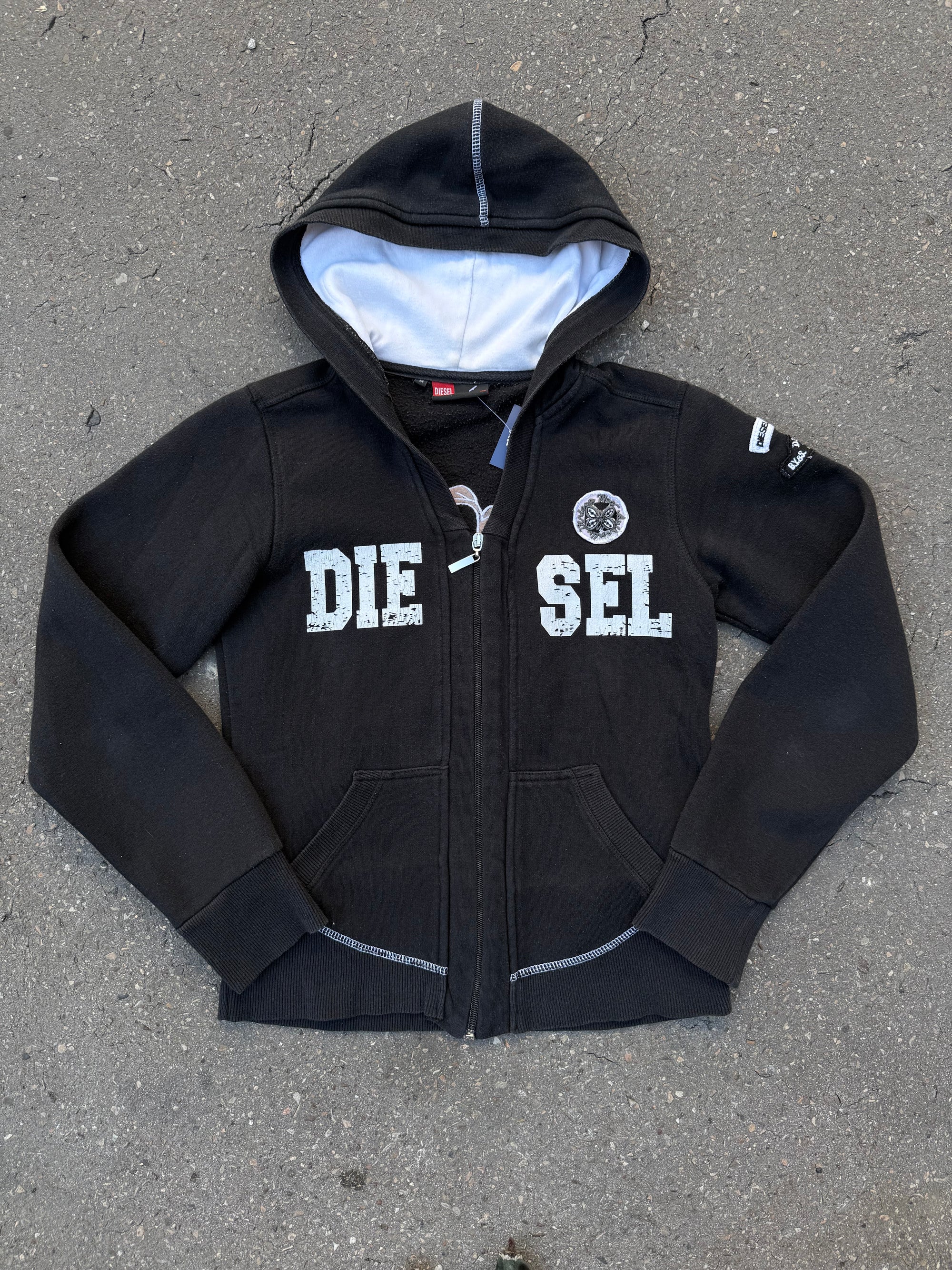 Ein schwarzer Zip Up Hoodie von Diesel mit dem Logo in weiß auf der Vorderseite und einem weißen Print auf der Rückseite