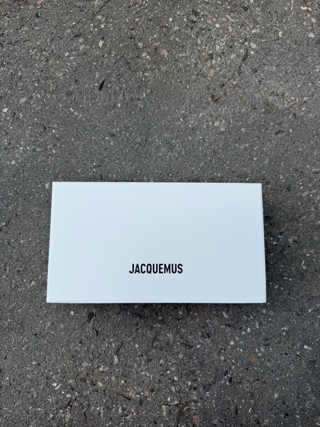Eine schwarze Sonnenbrille von Jacquemus mit goldenem Schriftzug auf der Seite