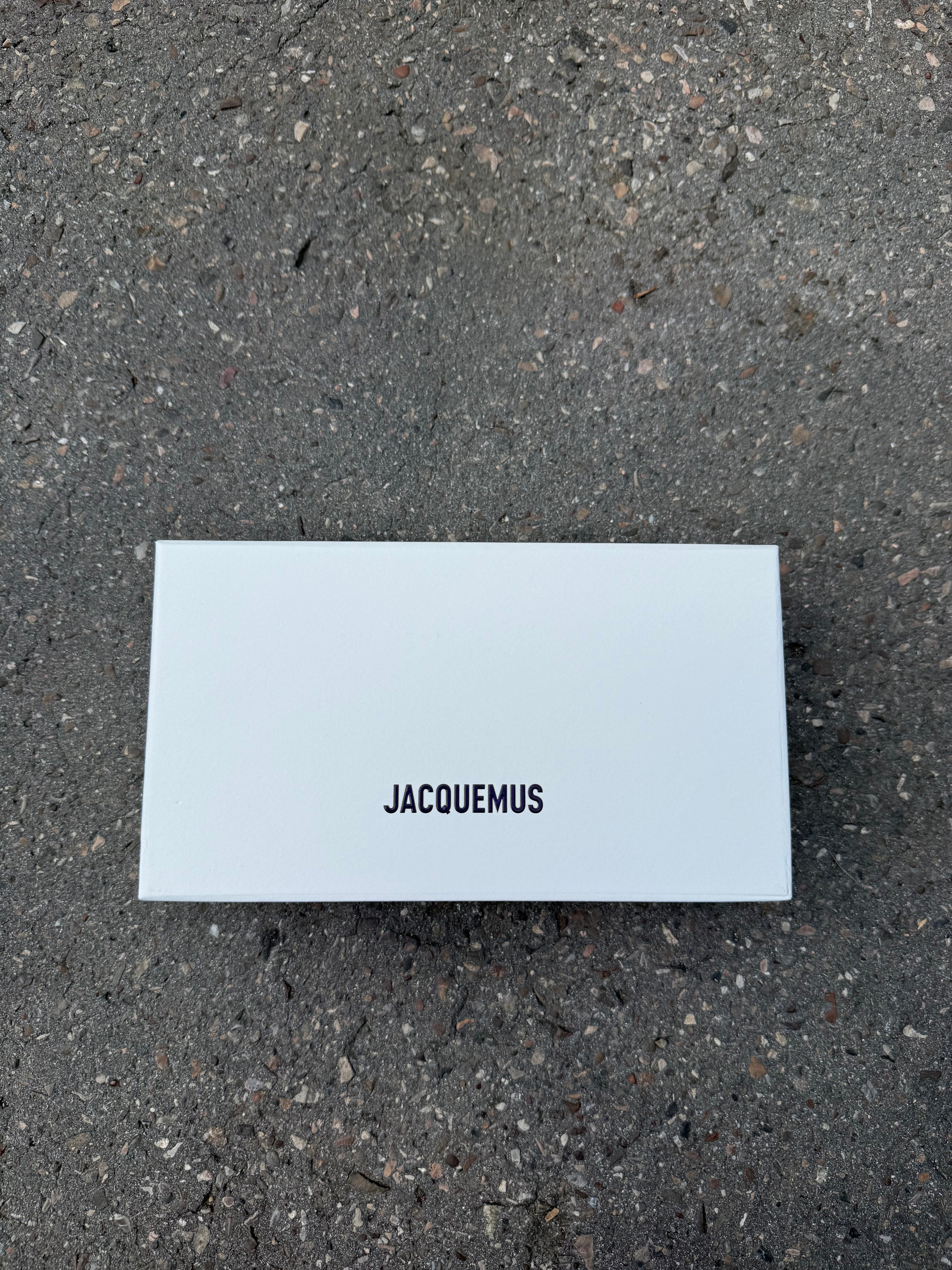 Eine schwarze Sonnenbrille von Jacquemus mit goldenem Schriftzug auf der Seite