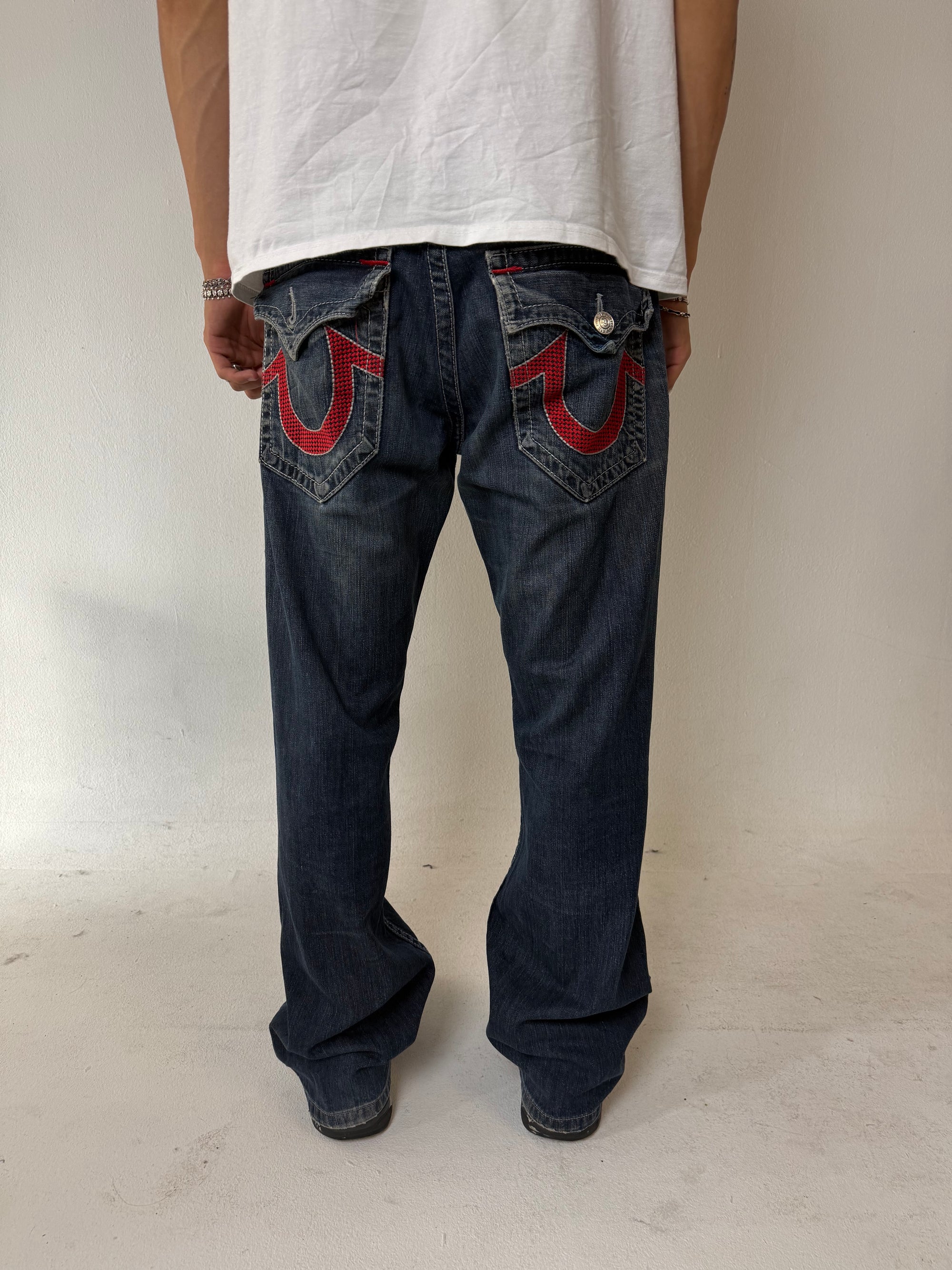 Eine dunkelblaue baggy True Religion mit roten Nähten und roten Hufeisen auf den Backpockets