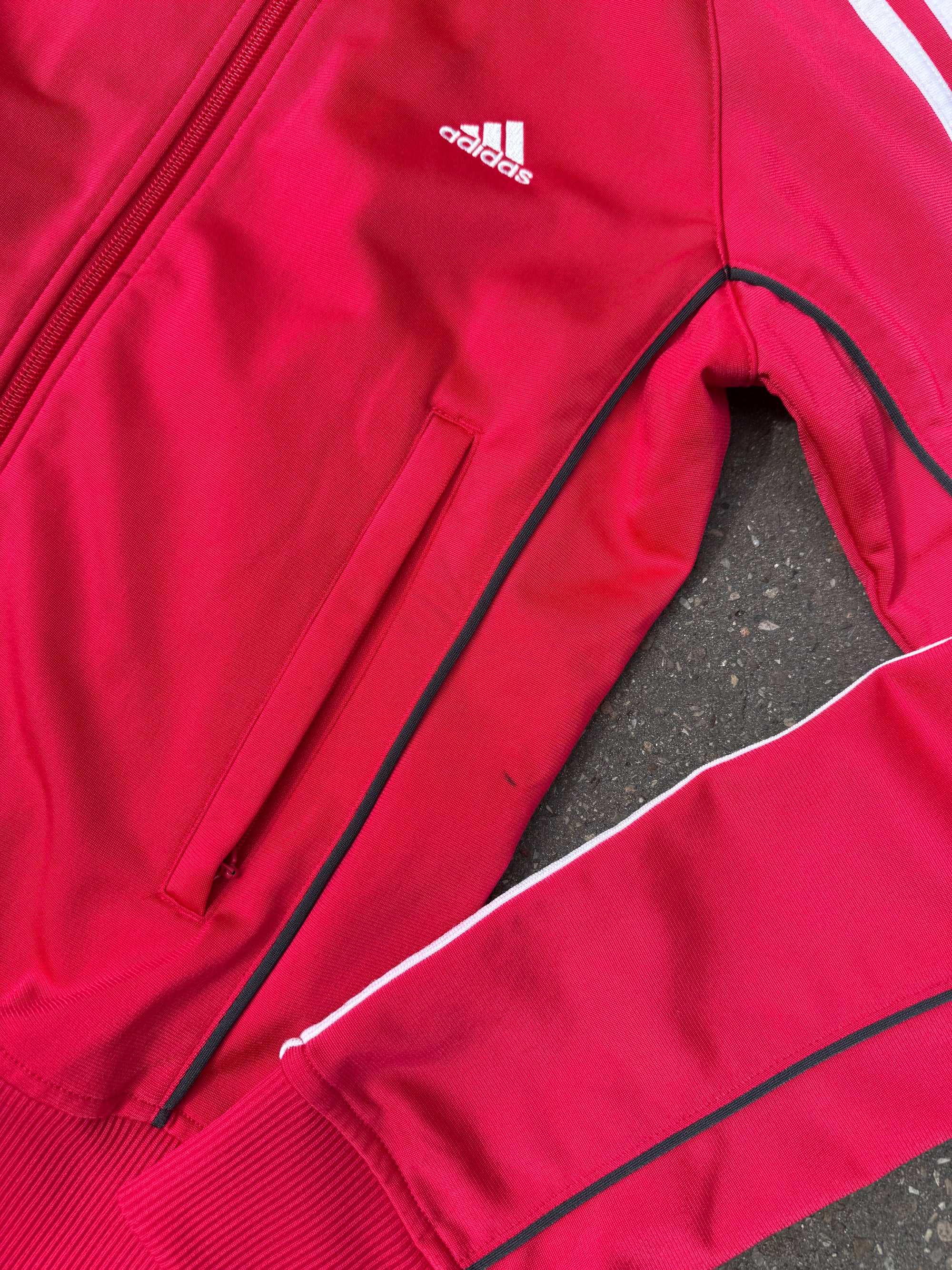 Eine Pinke Trackjacke von Adidas mit weißen Streifen auf den Ärmeln