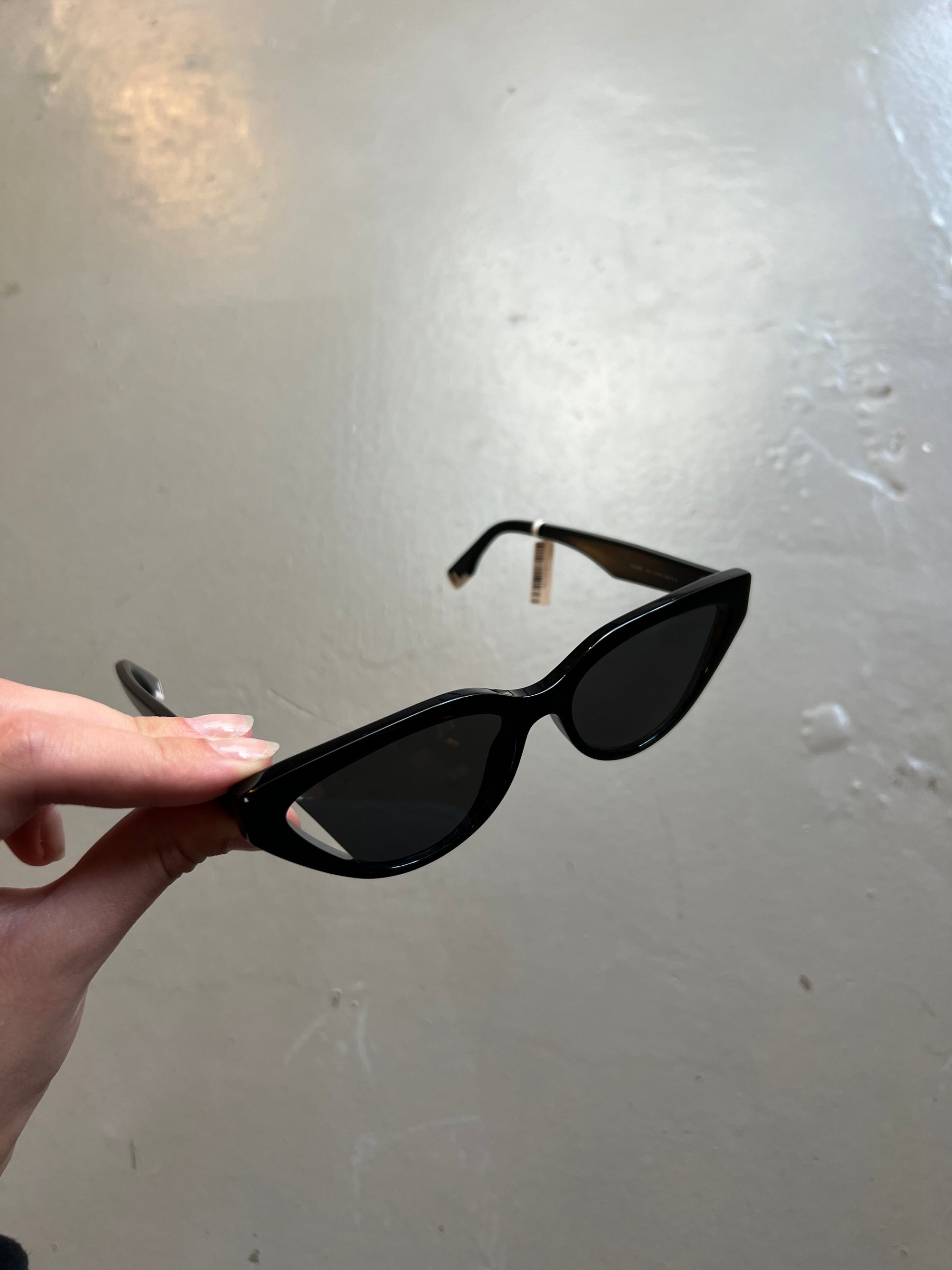 Produktbild von schwarzer Fendi Cat-Eye Sonnenbrille vor grauem Hintergrund.