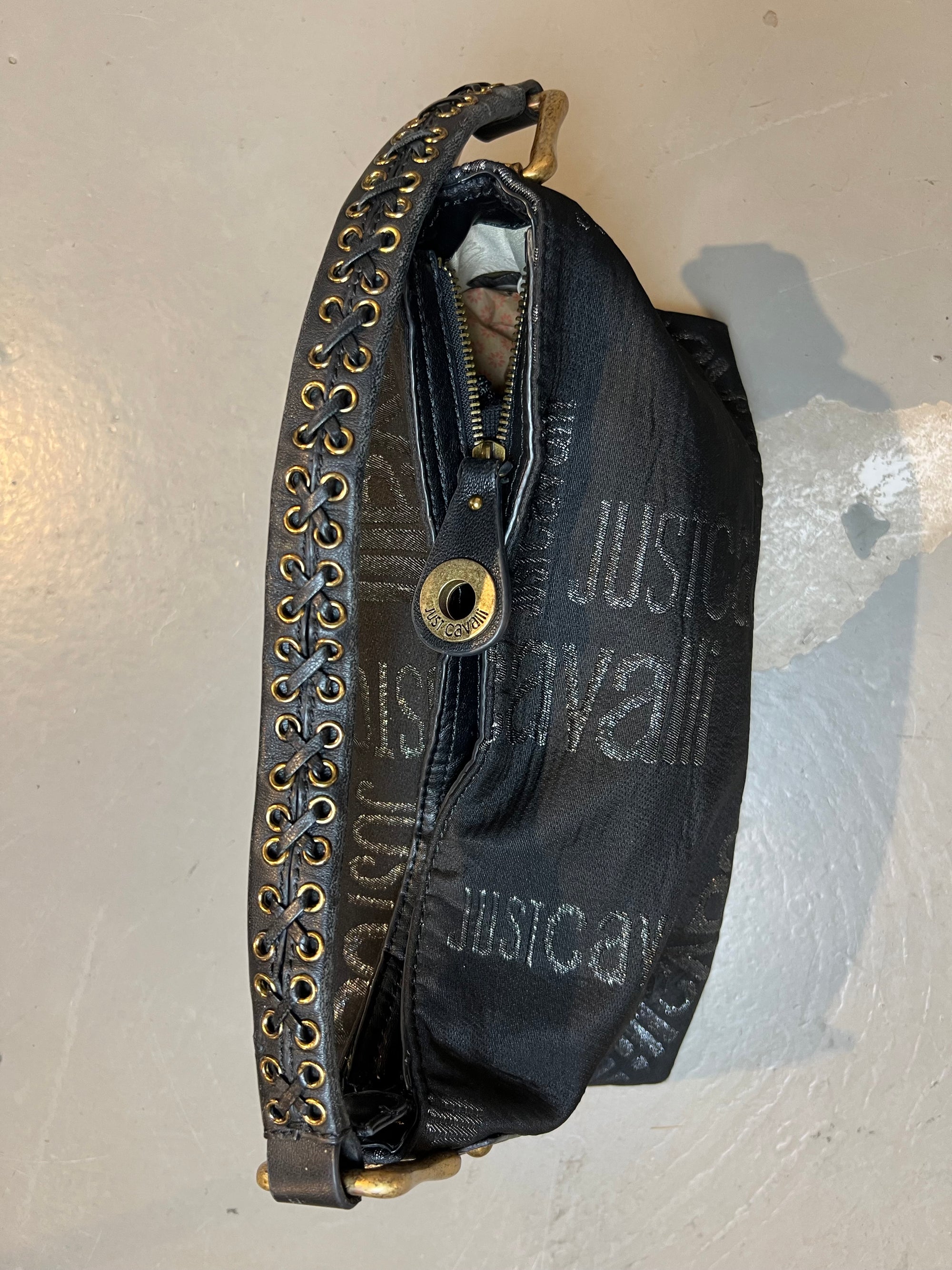 Schwarze schultertasche von just cavalli. Goldene Hardware, Monogramm Muster. Produktbild vor grauem Hintergrund. Von oben.