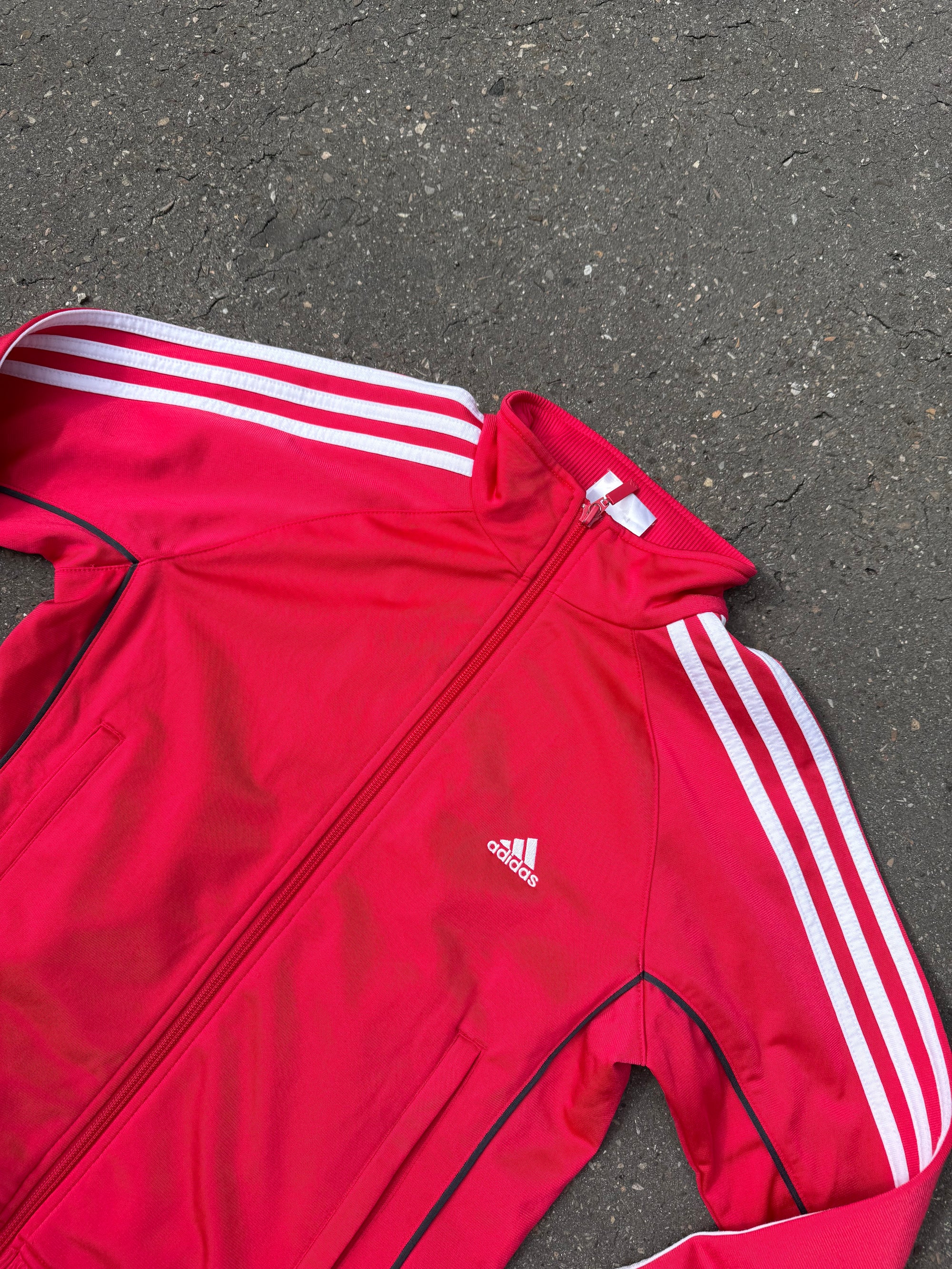 Eine Pinke Trackjacke von Adidas mit weißen Streifen auf den Ärmeln