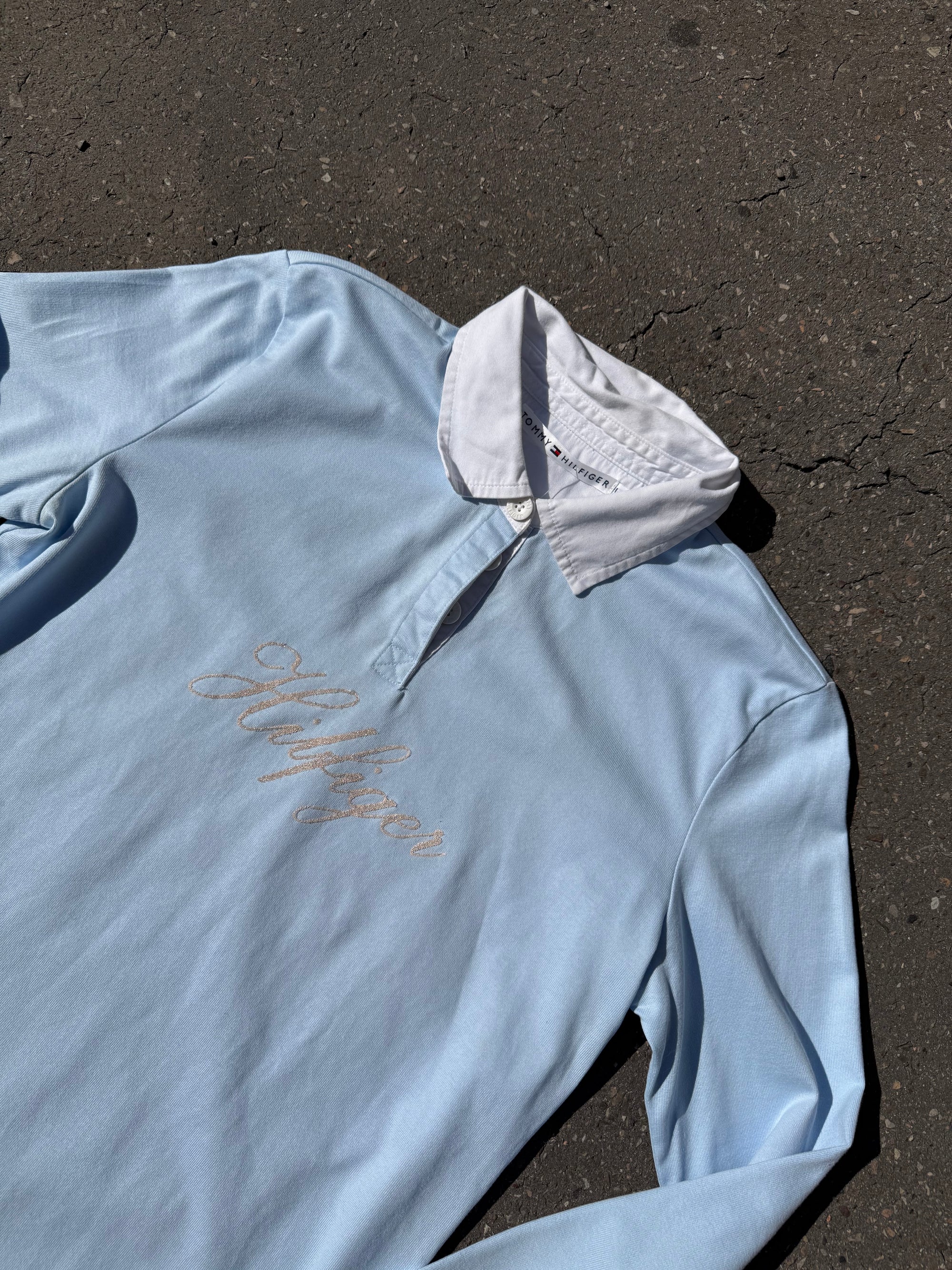Ein babyblaues langärmliges Polo mit weißem Kragen und Hilfiger in Silber auf der Brust geschrieben 