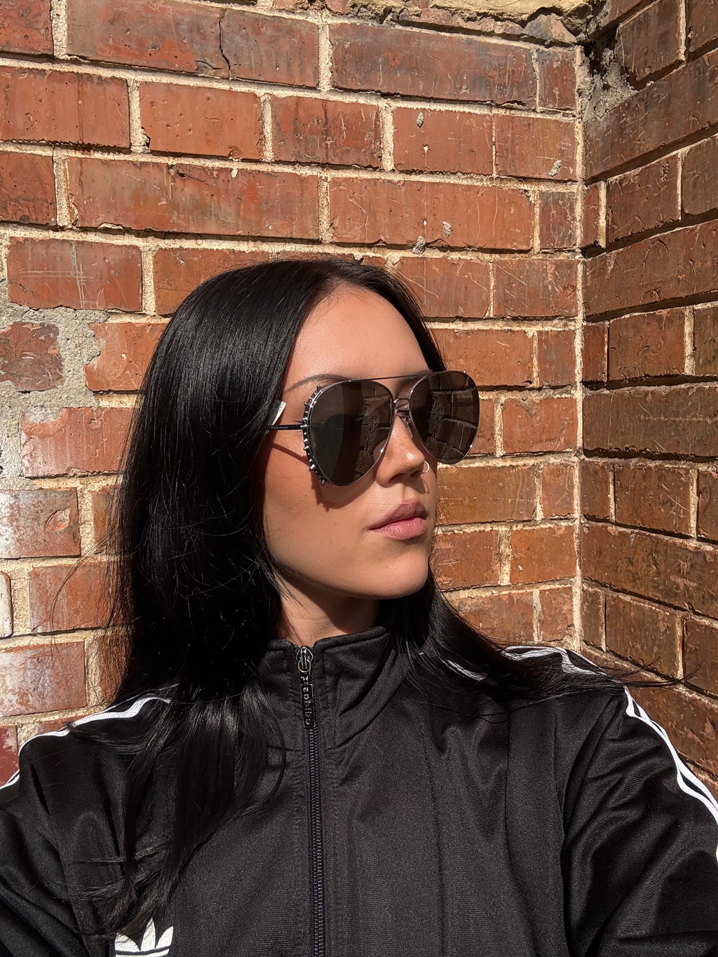 Eine Sonnenbrille von Alexander McQueen mit silbernen Nieten um die großen Gläser und dünnem Gestell 