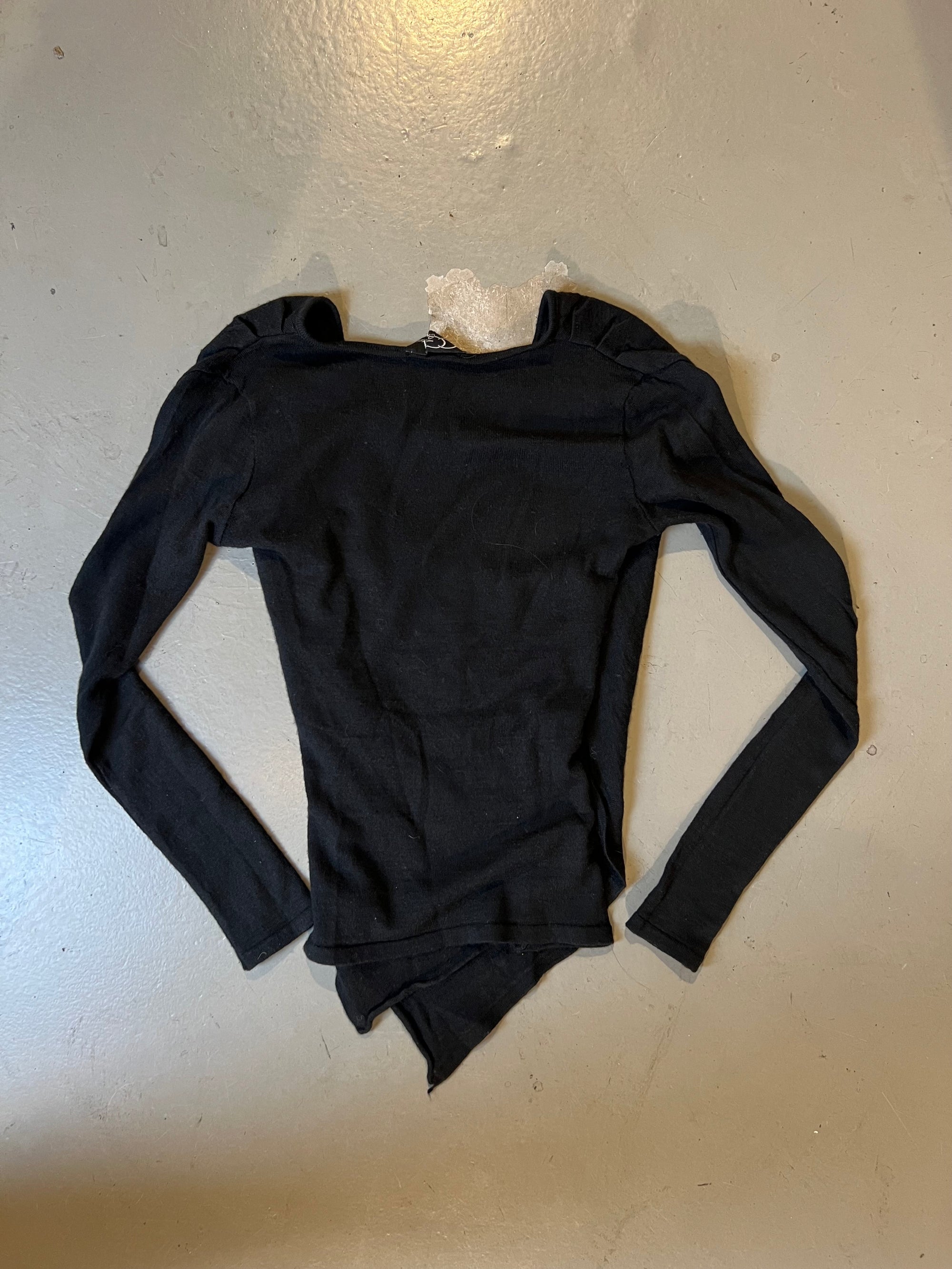 Produktbild von schwarzem Langarm top hinten auf grauem Boden