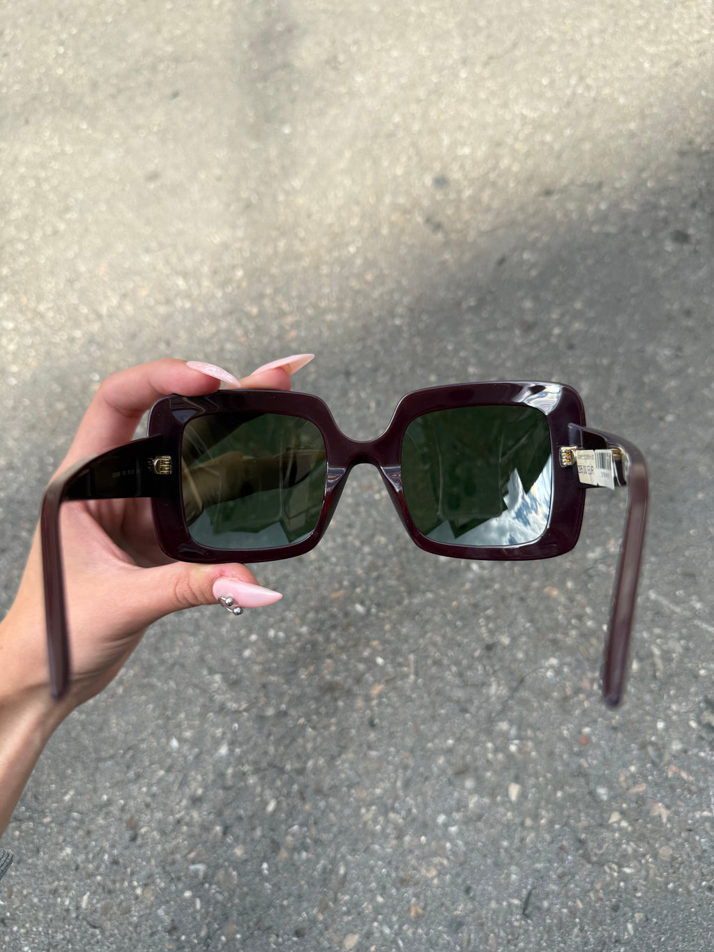 Eine burgunderrote Sonnenbrille von Gucci mit dem Logo in Gold an der Seite und großen quadratischen Gläsern