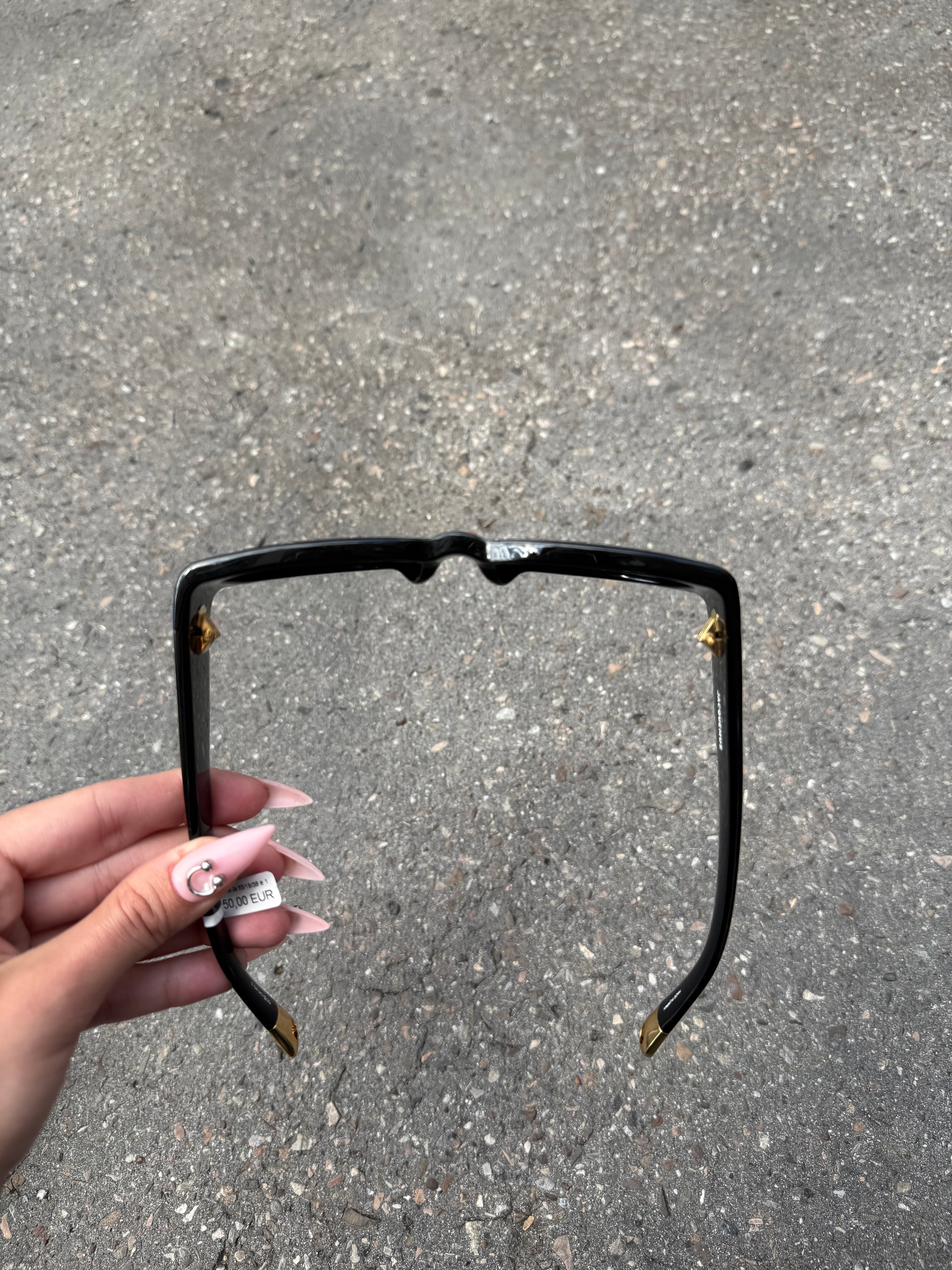 Eine schwarze Sonnenbrille von Jacquemus mit goldenem Schriftzug auf der Seite