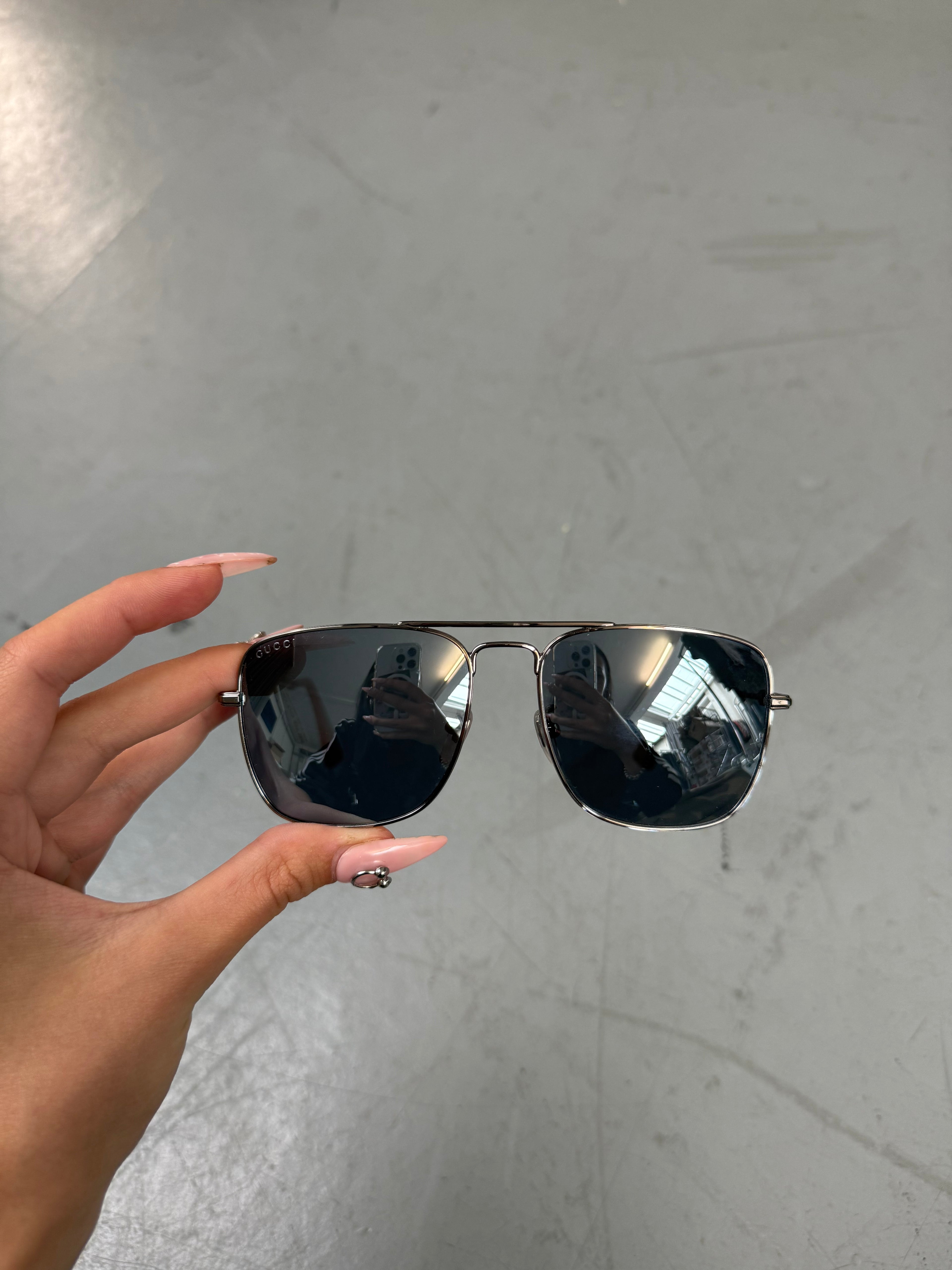 Eine eckige Sonnenbrille von gucci mit dunklen Gläsern und roten und grünen Elementen an den Bügeln 