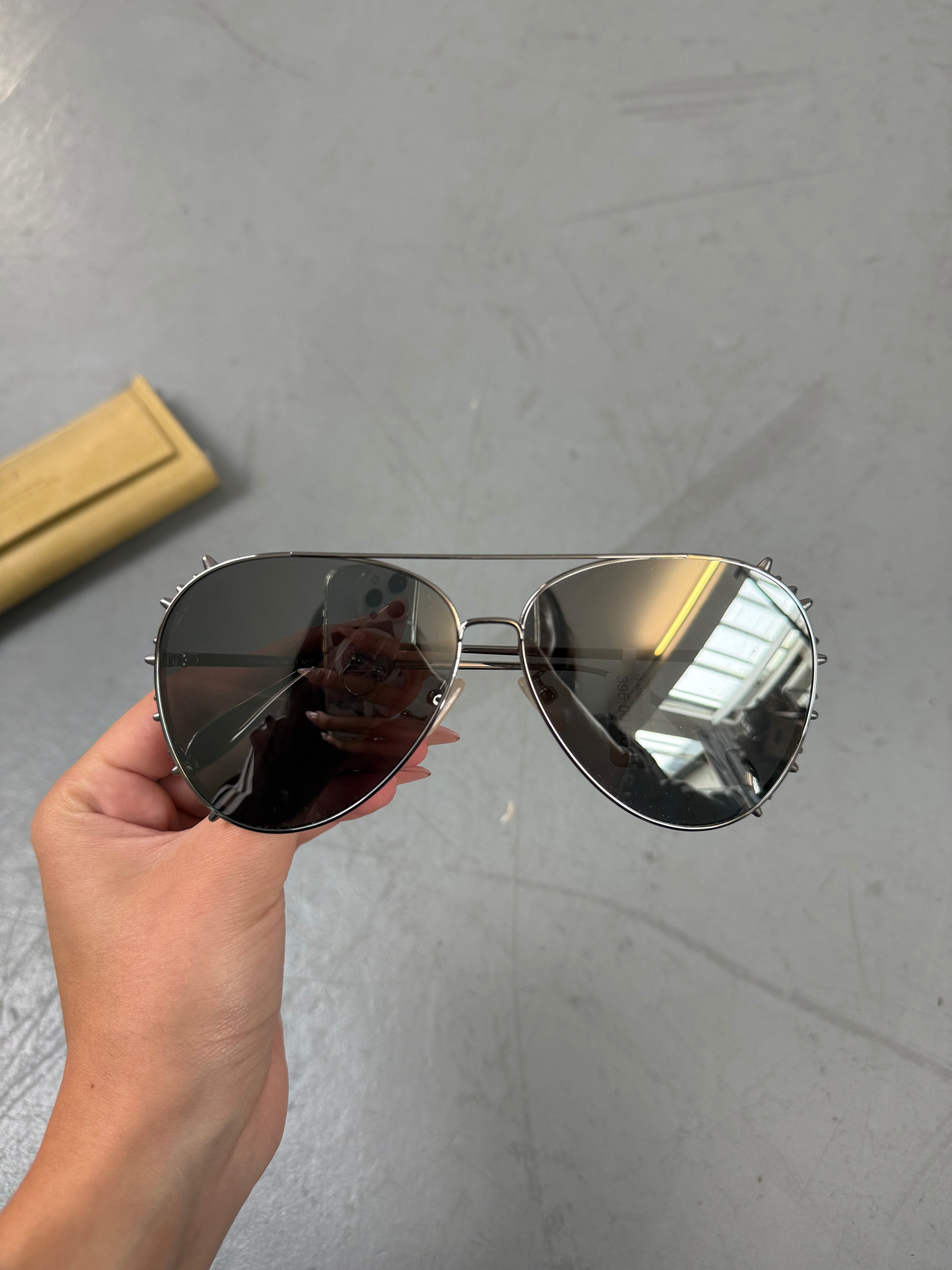 Eine Sonnenbrille von Alexander McQueen mit silbernen Nieten um die großen Gläser und dünnem Gestell 