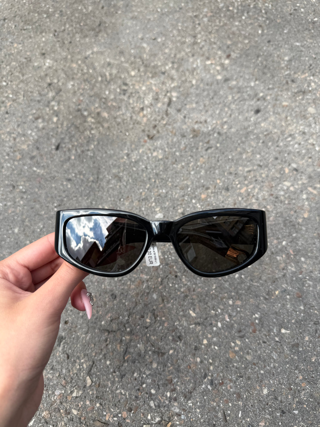 Eine schwarze Sonnenbrille von Jacquemus mit goldenem Schriftzug auf der Seite